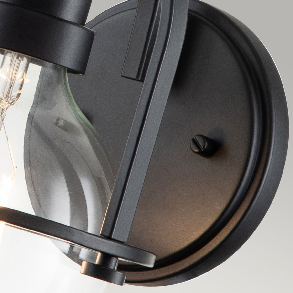 Close-up of the black circular wall plate and part of the glass shade.