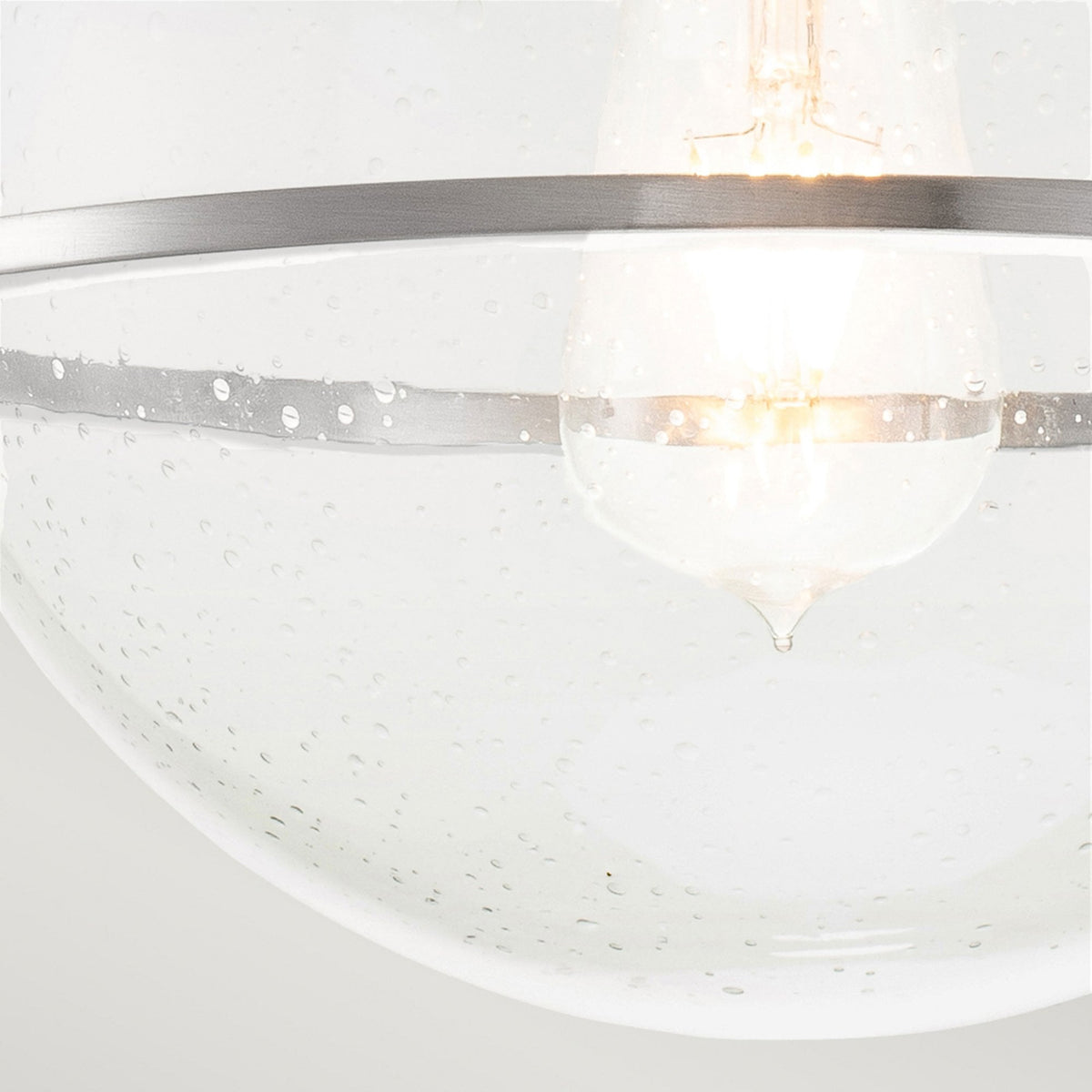 A close-up of the seeded glass shade and the vintage-style bulb within.