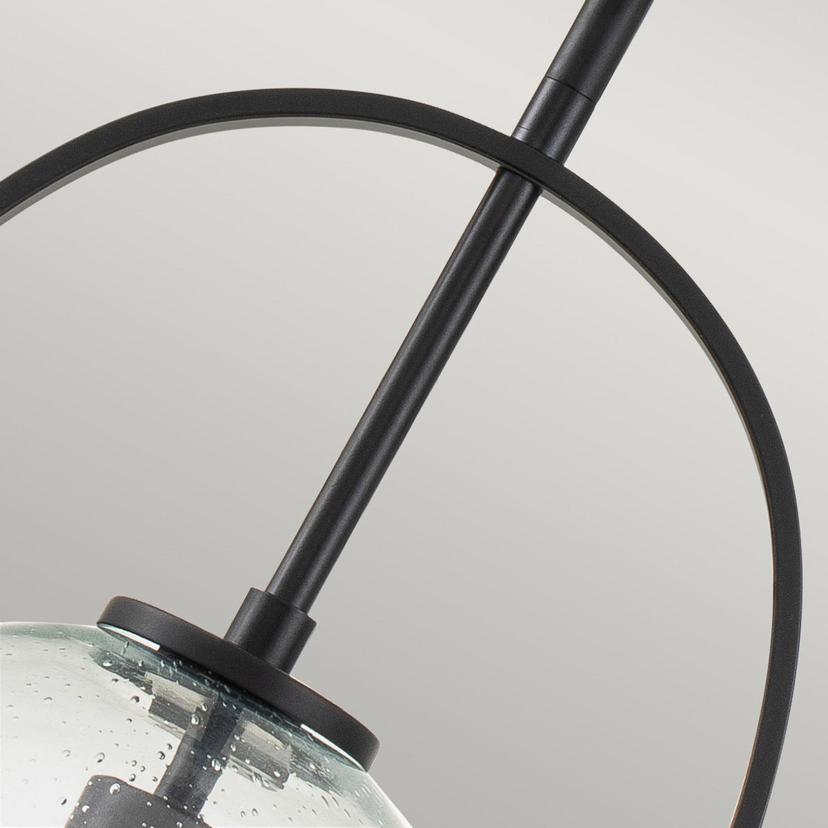 Close-up of the black metal frame and clear seeded glass shade of the pendant light.