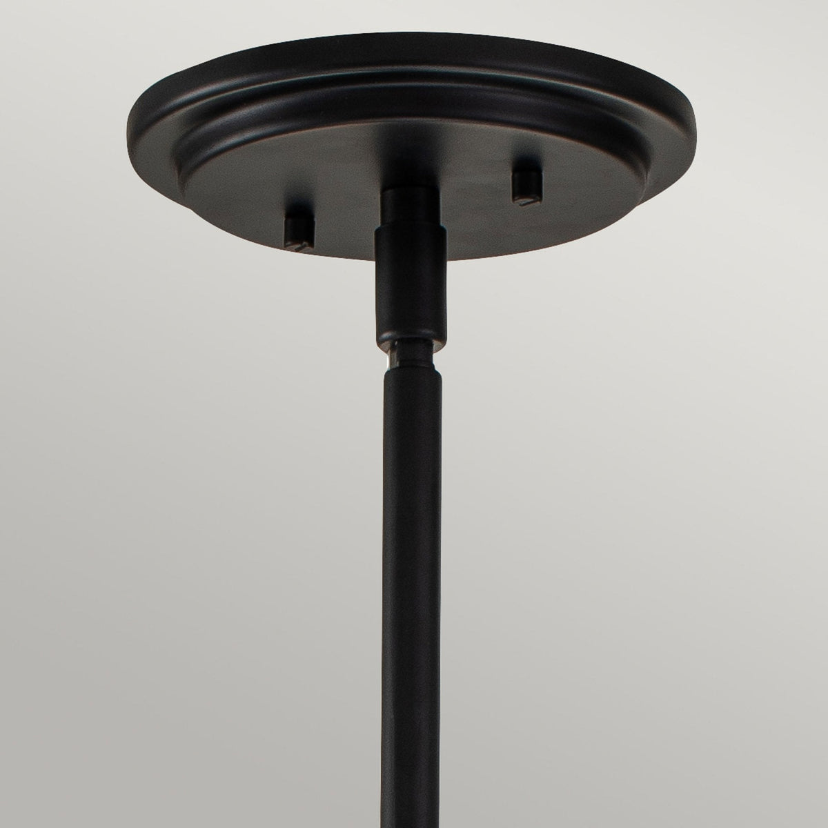 Close-up of the round black ceiling rose and rod of the pendant light fixture.