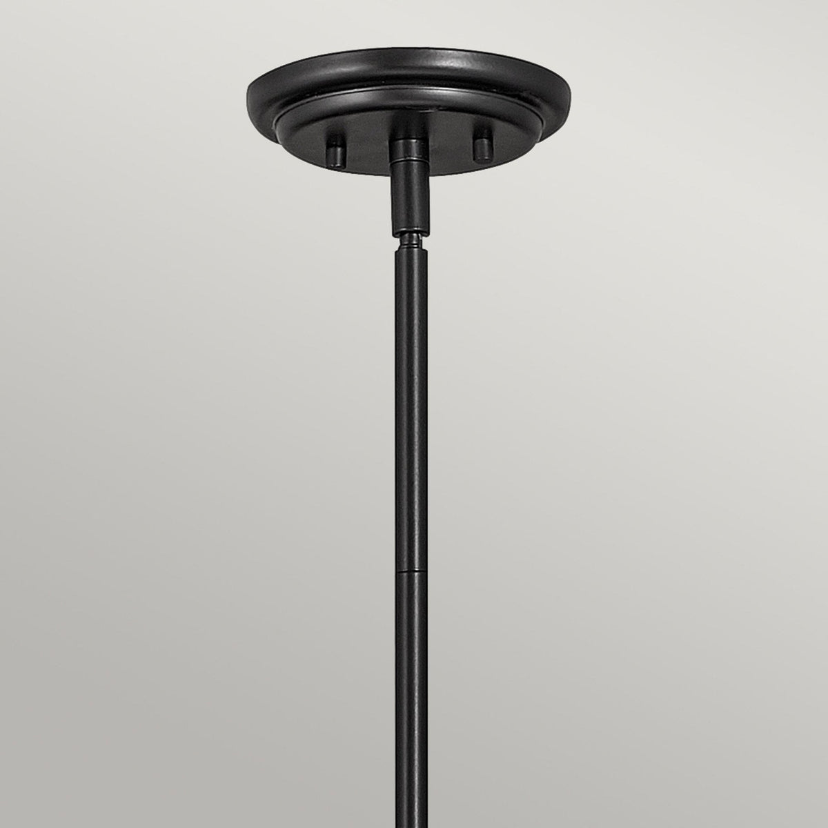 A close-up of the black ceiling mount and stem of the pendant light.