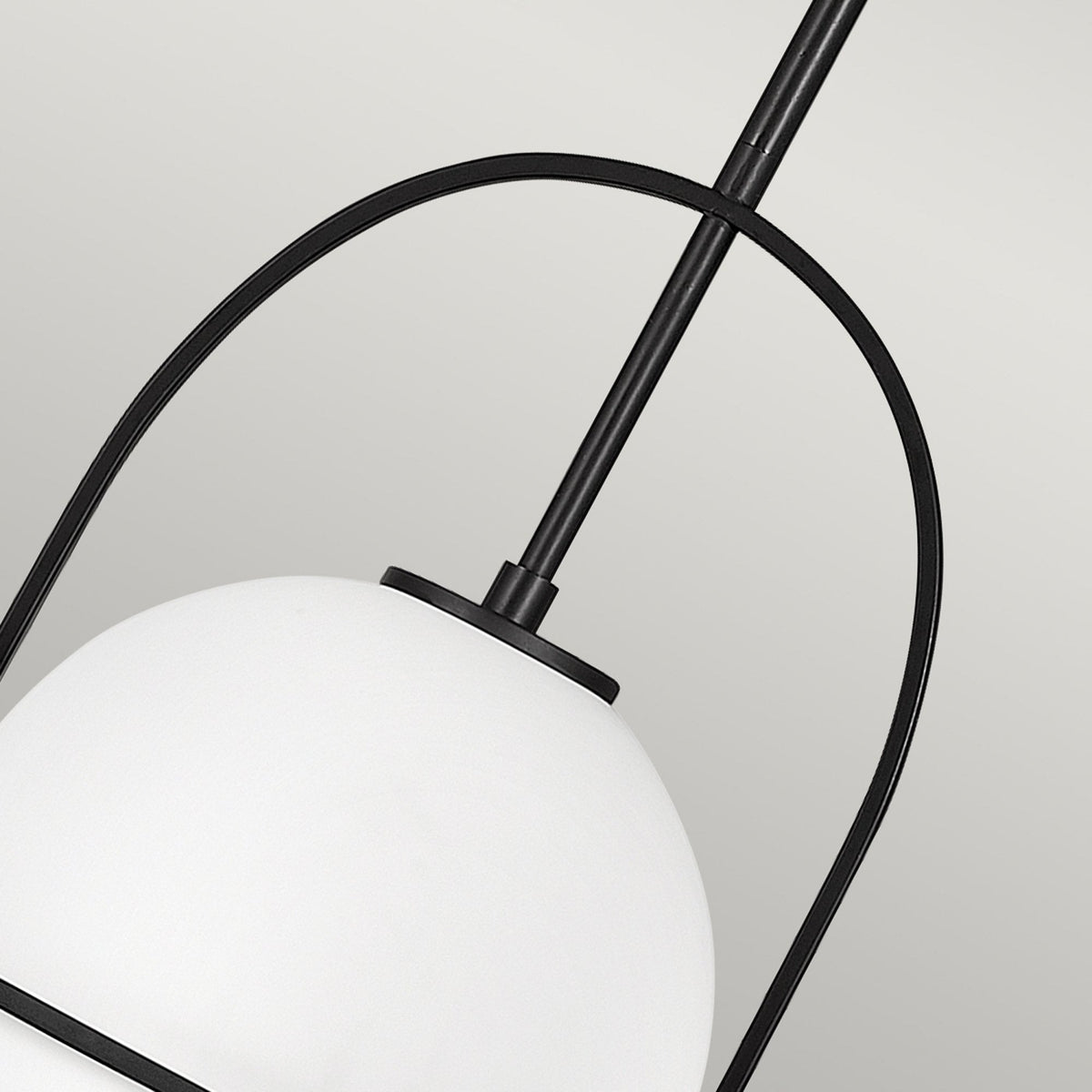 A close-up showing the top portion of the white spherical shade and the black frame.