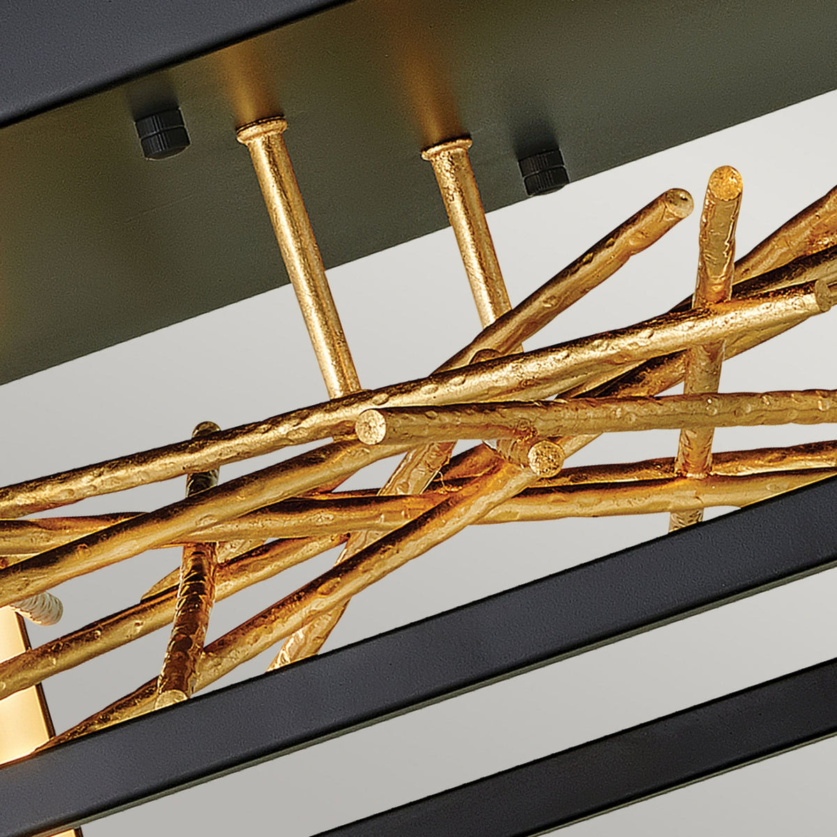 Detailed view of the gold twig-like elements and mounting hardware of the light fixture.