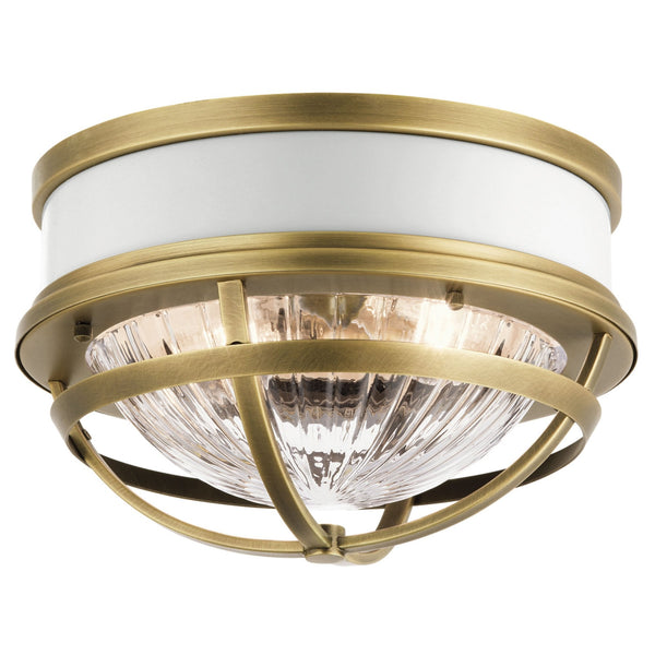 A flush mount light fixture with an antique brass finish and a ribbed glass diffuser.