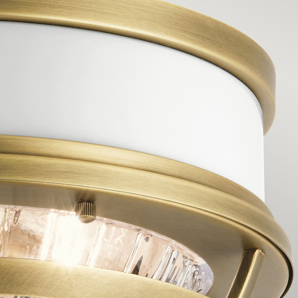 Close-up of the antique brass rim and white band of a ceiling light fixture.