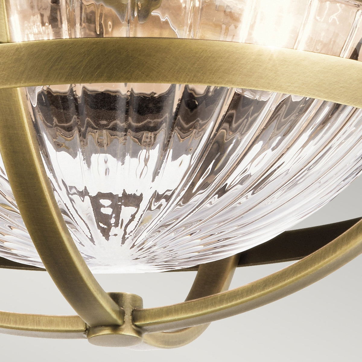 A close-up of the ribbed glass diffuser and antique brass frame of a ceiling light.