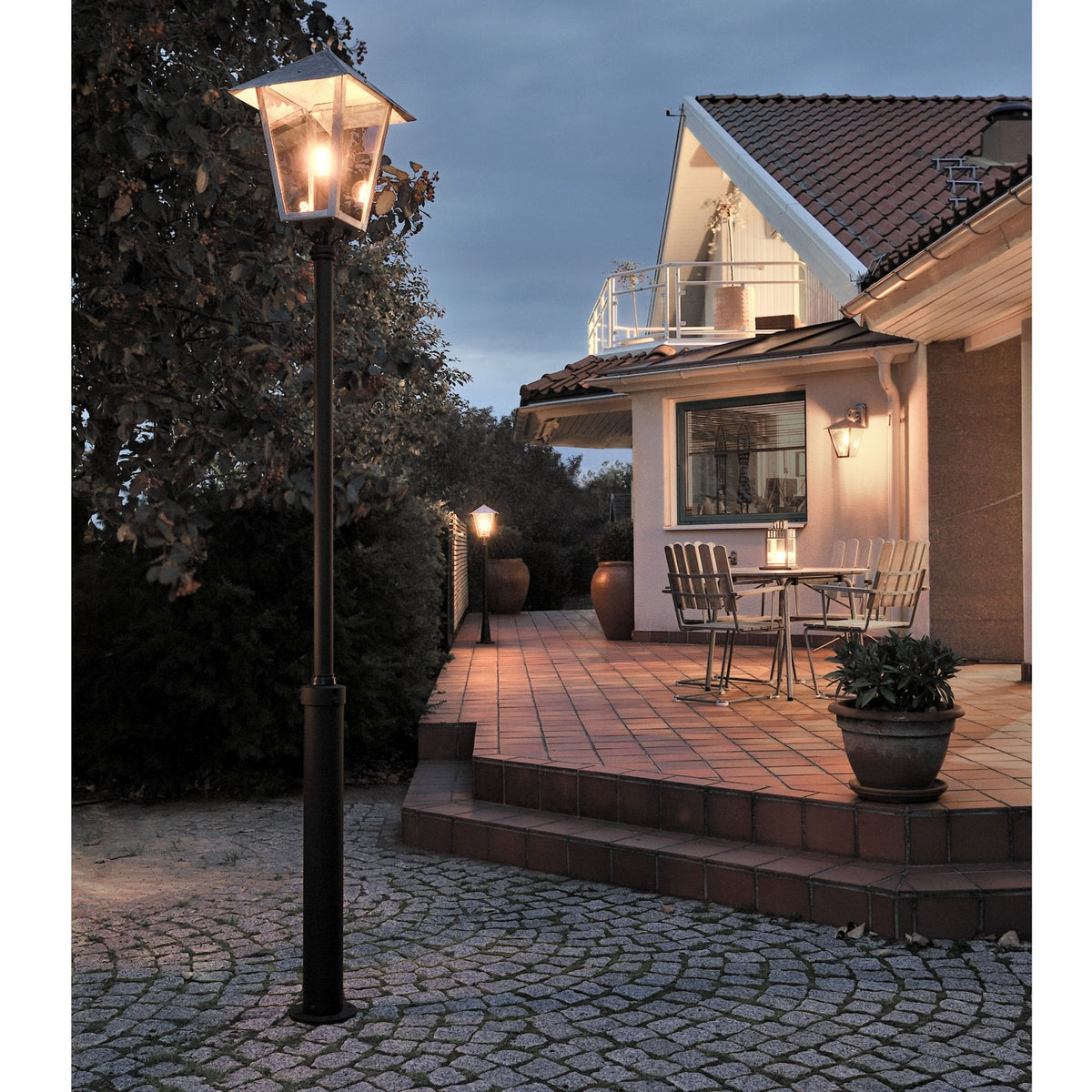 An outdoor lamp post illuminates a home's patio area at dusk, enhancing outdoor living.