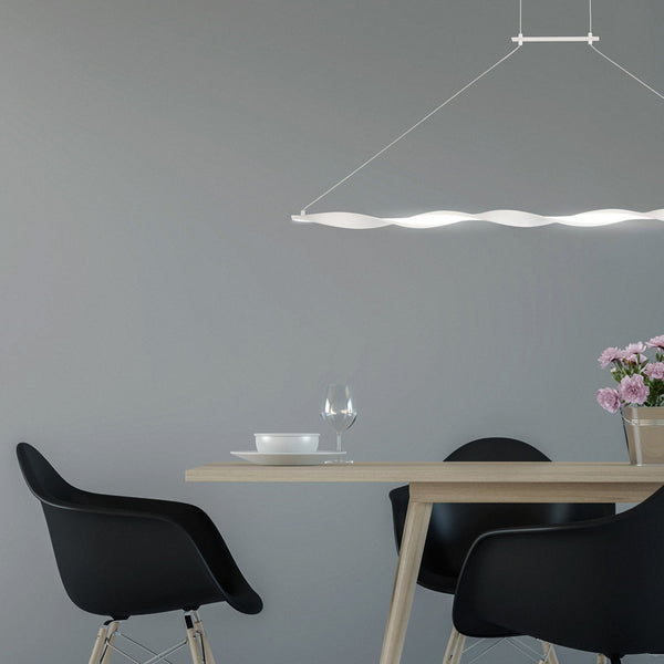 Modern wave-shaped LED pendant light illuminating a dining table with black chairs.