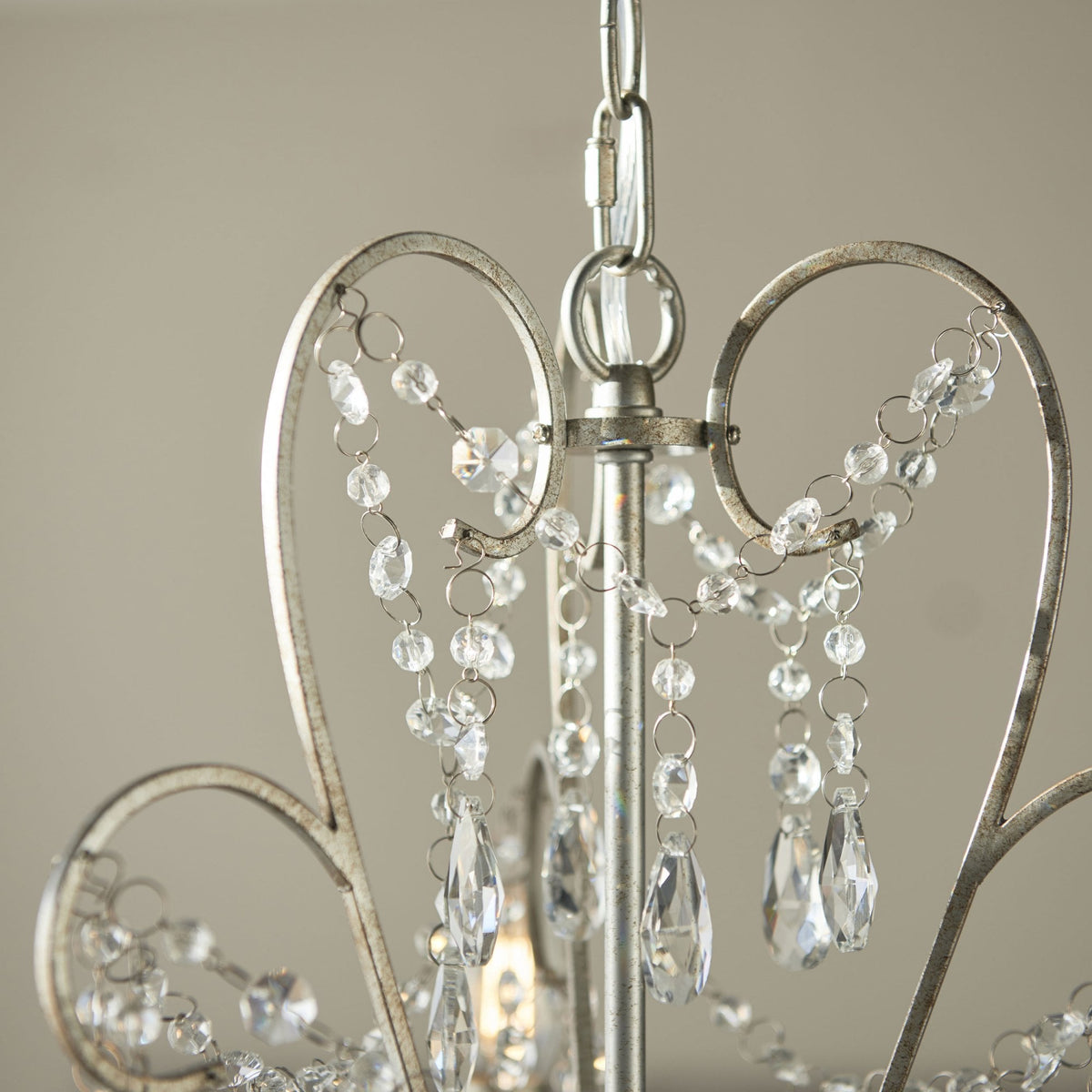 Close-up of the top of a chandelier with heart-shaped metalwork and crystal beads.