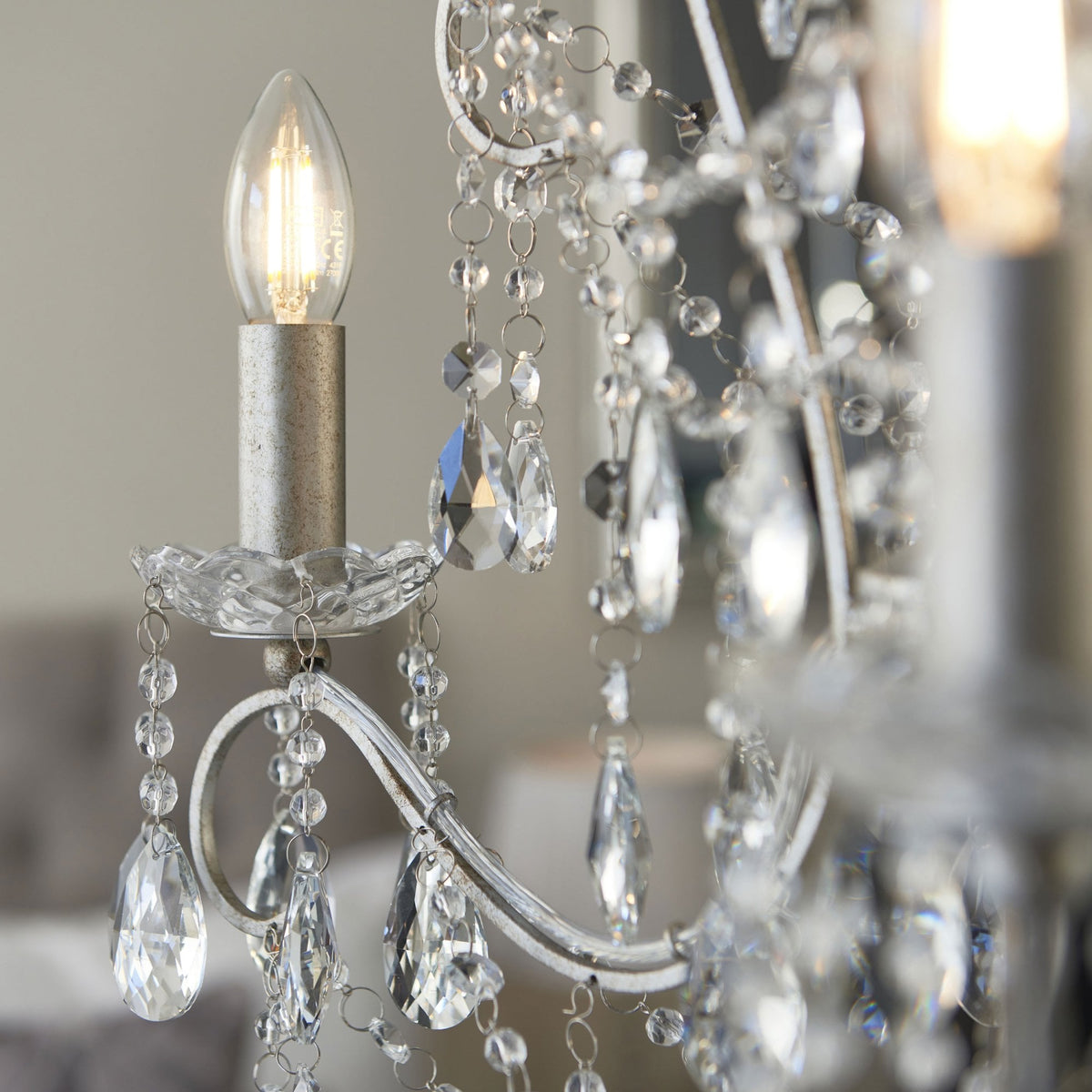 Close-up of a lit candle-style bulb and crystal accents on a chandelier.