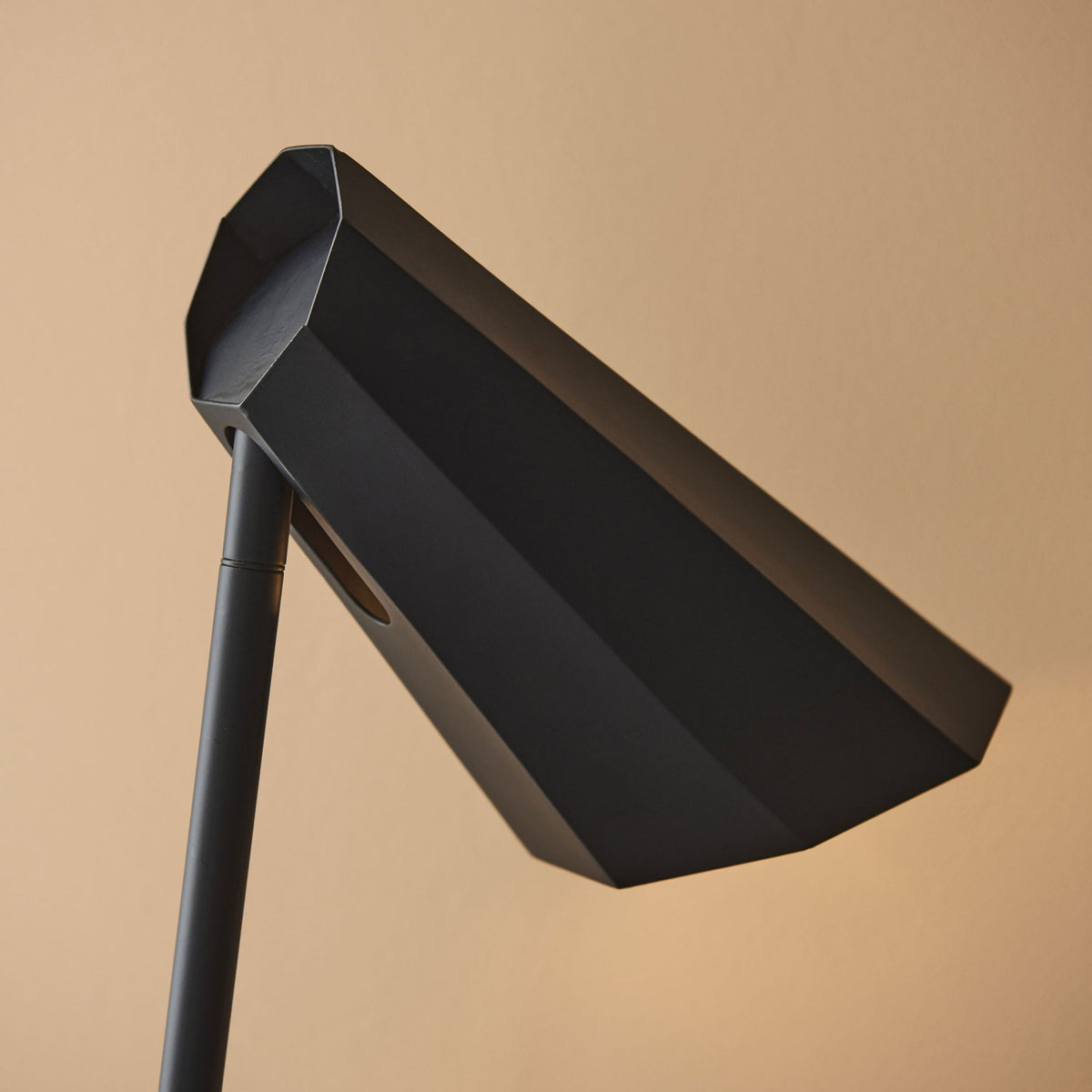 Close-up of the black geometric shade of a modern desk lamp.