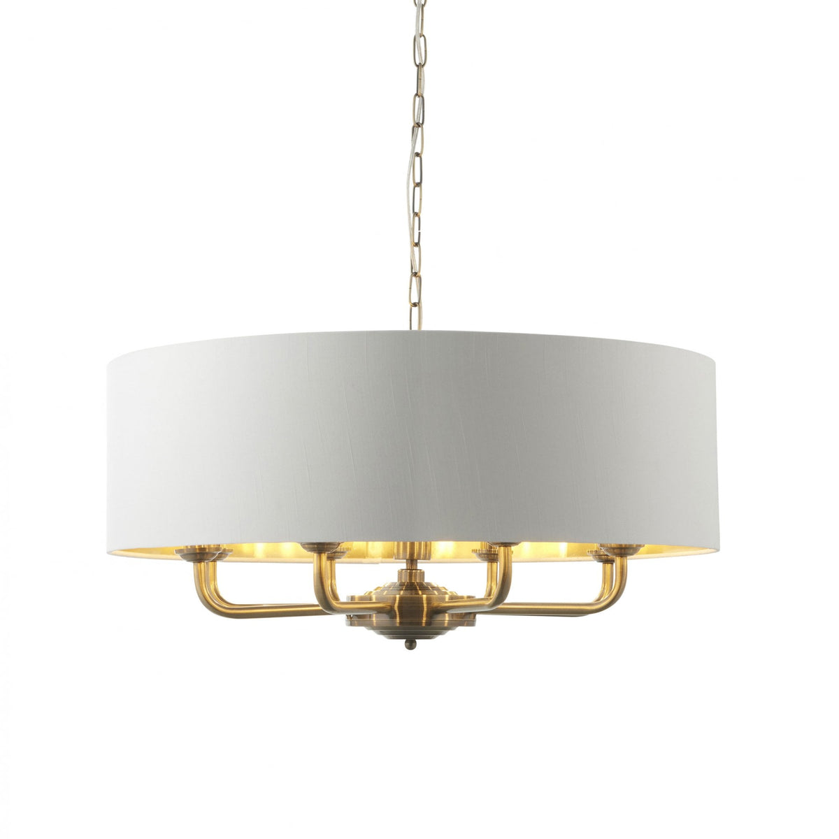A large, round pendant light with a white drum shade and brass interior hangs from a chain.