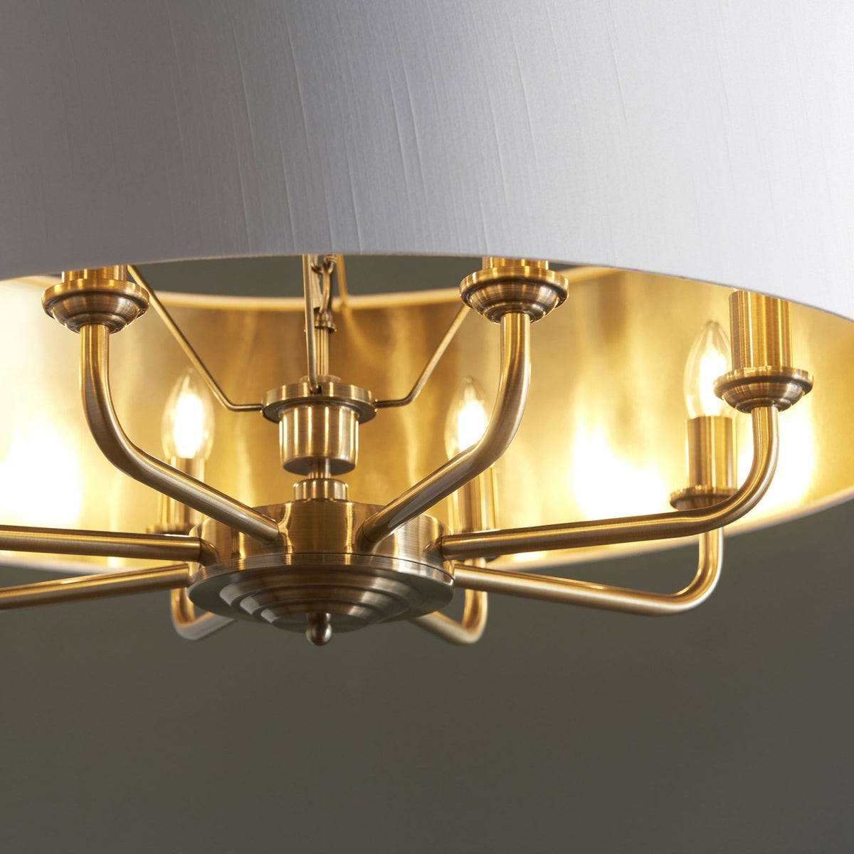 Close-up of the brass interior and exposed bulbs of a large, round pendant light.