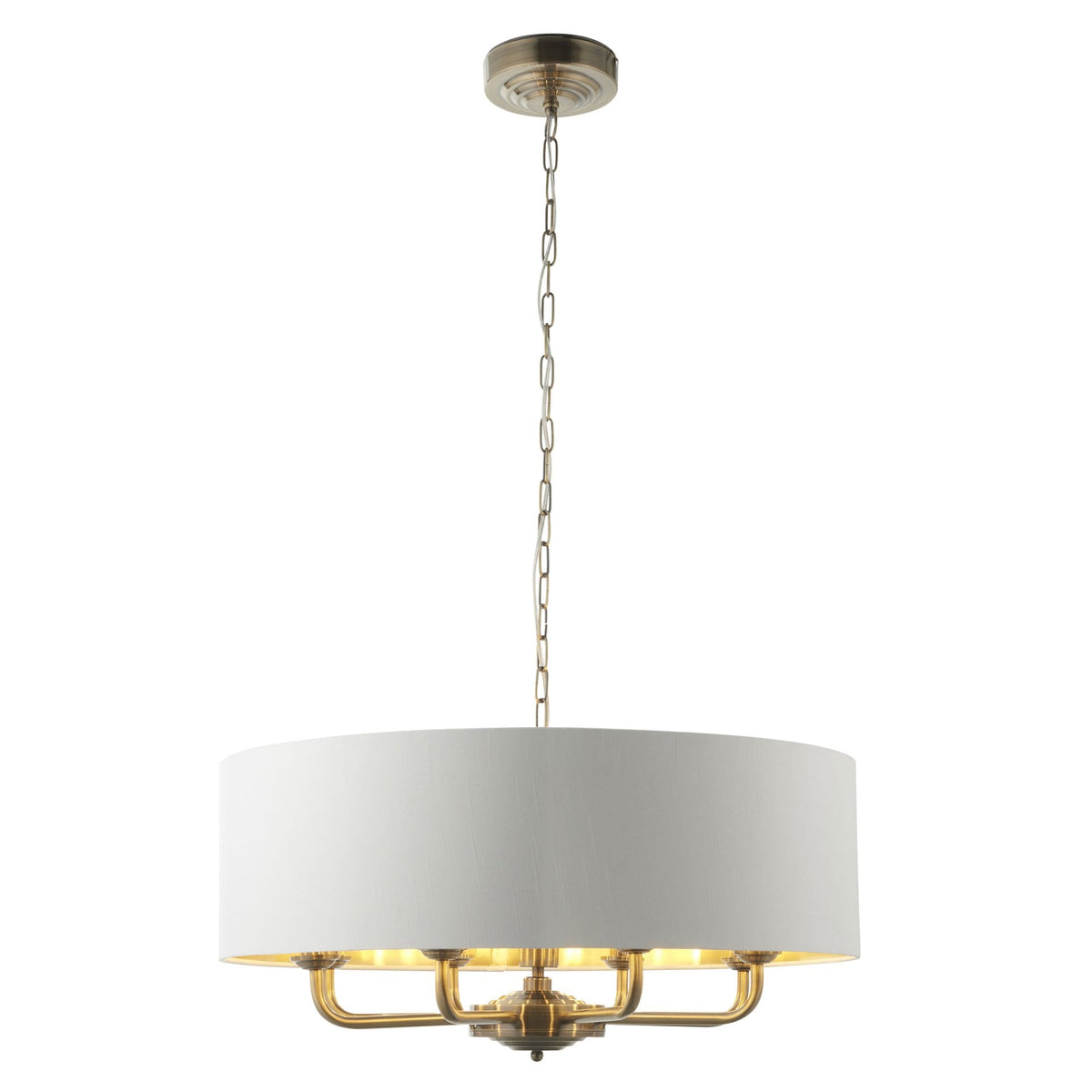 A large, round pendant light with a white drum shade and brass interior hangs from a chain.
