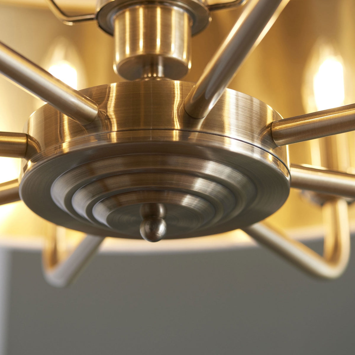 Close-up of the brass fixture details and arms of a large pendant light.