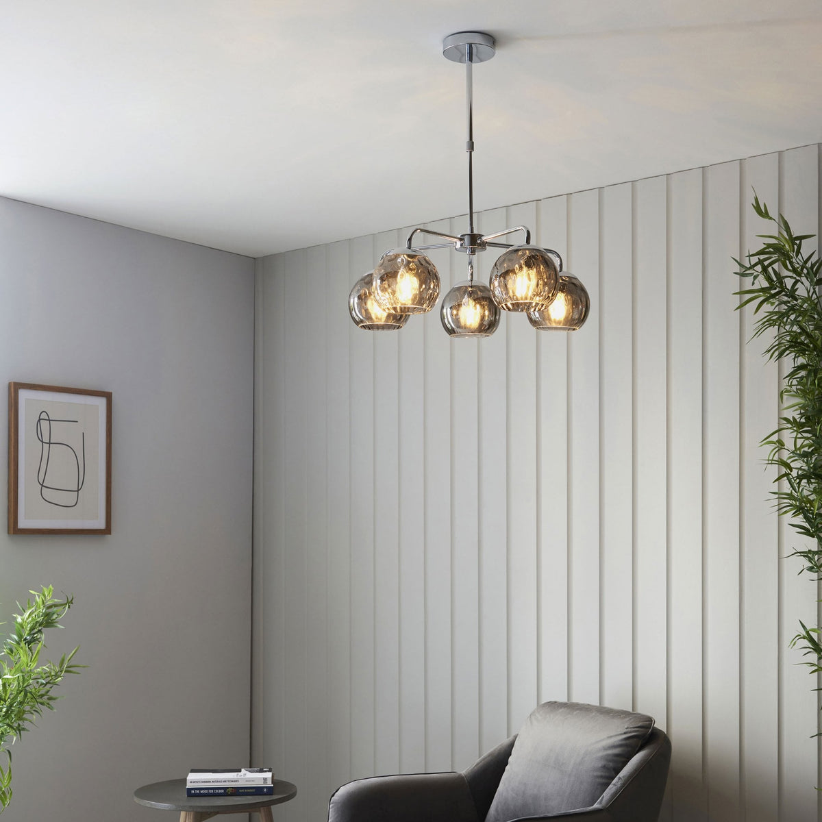 A modern living room featuring a chrome ceiling light with five smoked glass orb shades, providing ambient lighting.