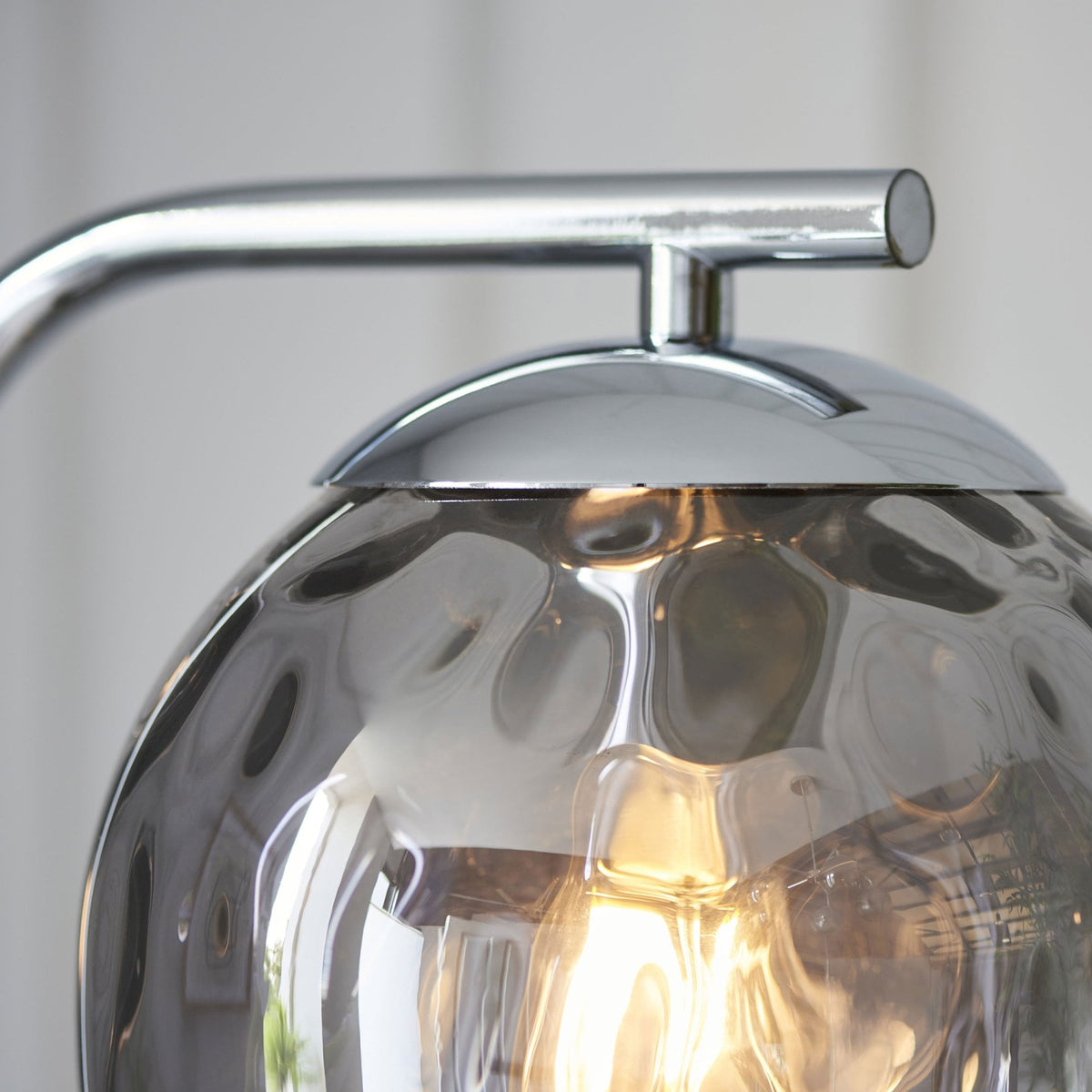 Close-up of the top of a chrome floor lamp, highlighting the textured smoked glass shade and chrome fitting.