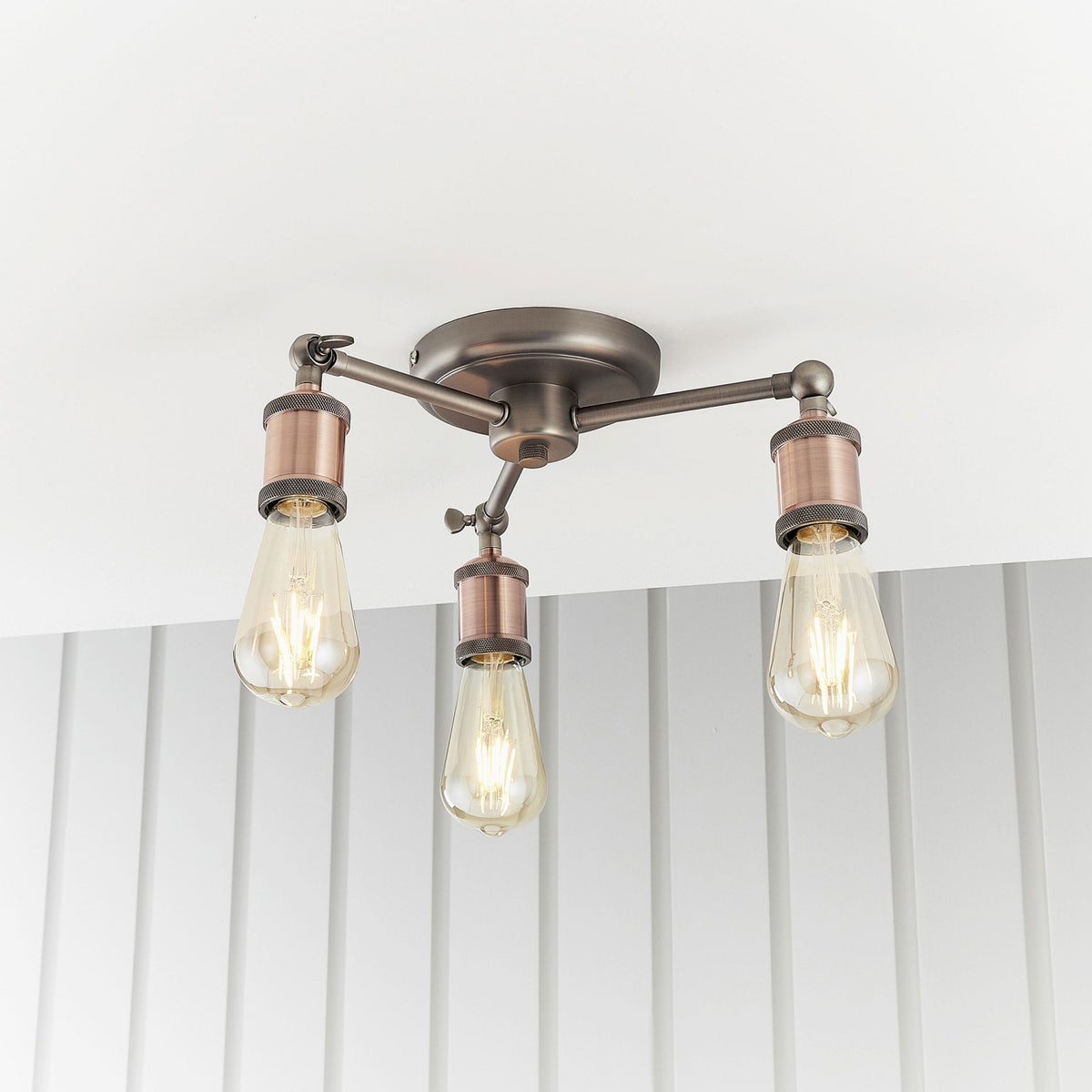 Three-light semi-flush ceiling fixture with antique copper bulb holders and exposed bulbs.