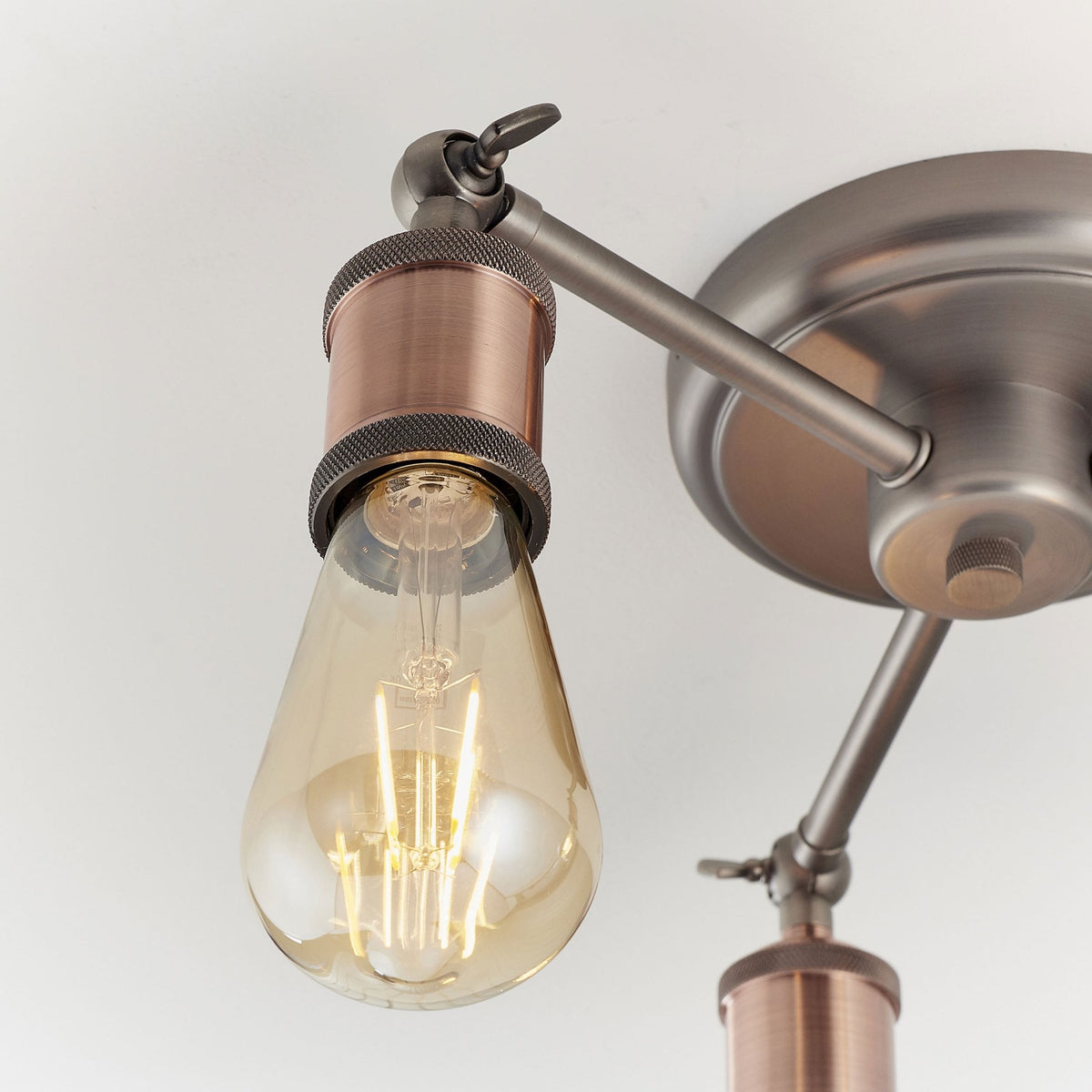 Close-up of a single light on a semi-flush ceiling fixture with an antique copper bulb holder.