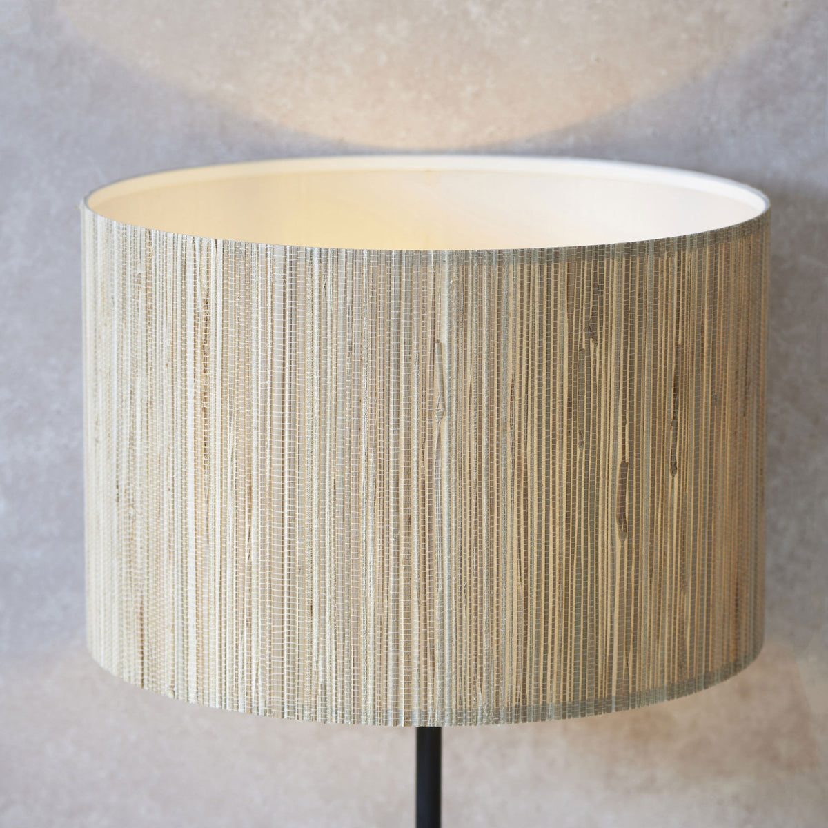 Close-up of a lamp shade made from natural woven material, showing its texture and warm inner glow.