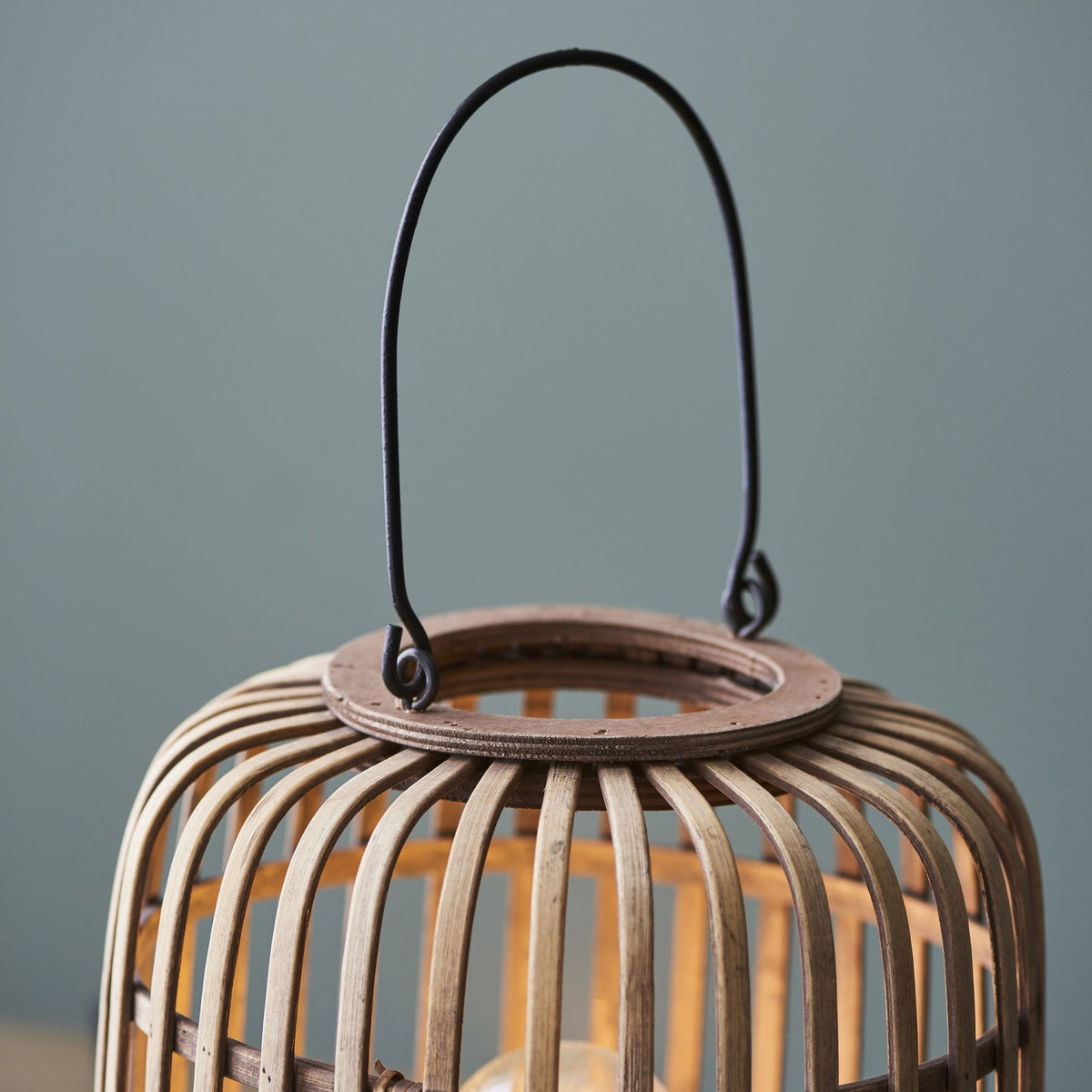 A close-up of the handle and top of a bamboo cage table lamp.