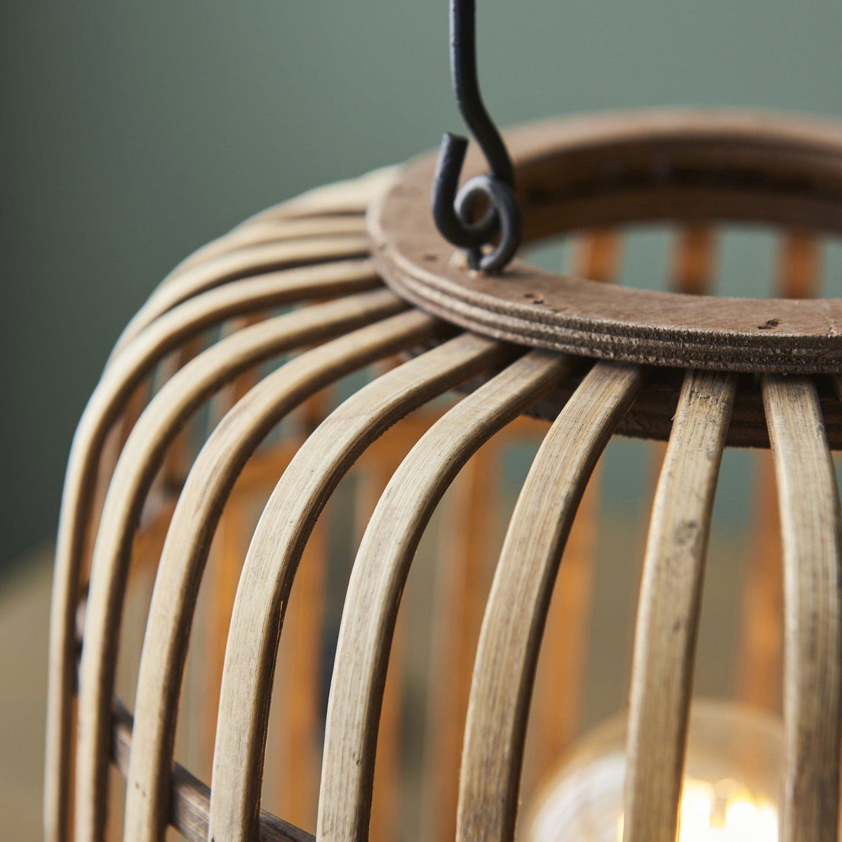 A close-up of the top and handle attachment of a bamboo cage table lamp.