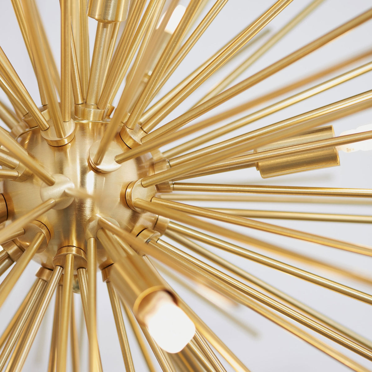 Close-up of a gold sputnik chandelier, showing the central sphere and radiating arms with light bulbs.
