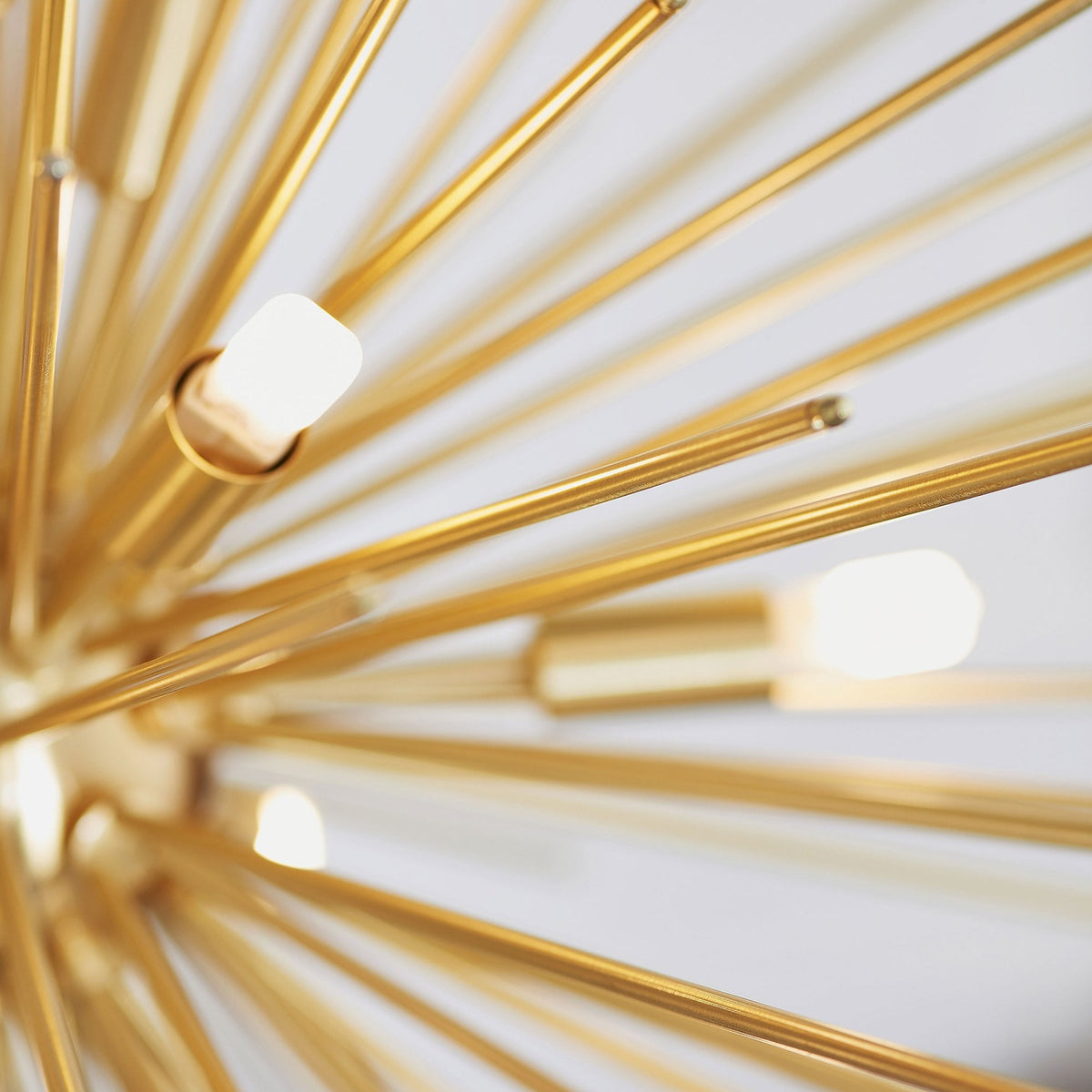 Macro shot of the gold sputnik chandelier, focusing on the illuminated bulbs and metallic arms.