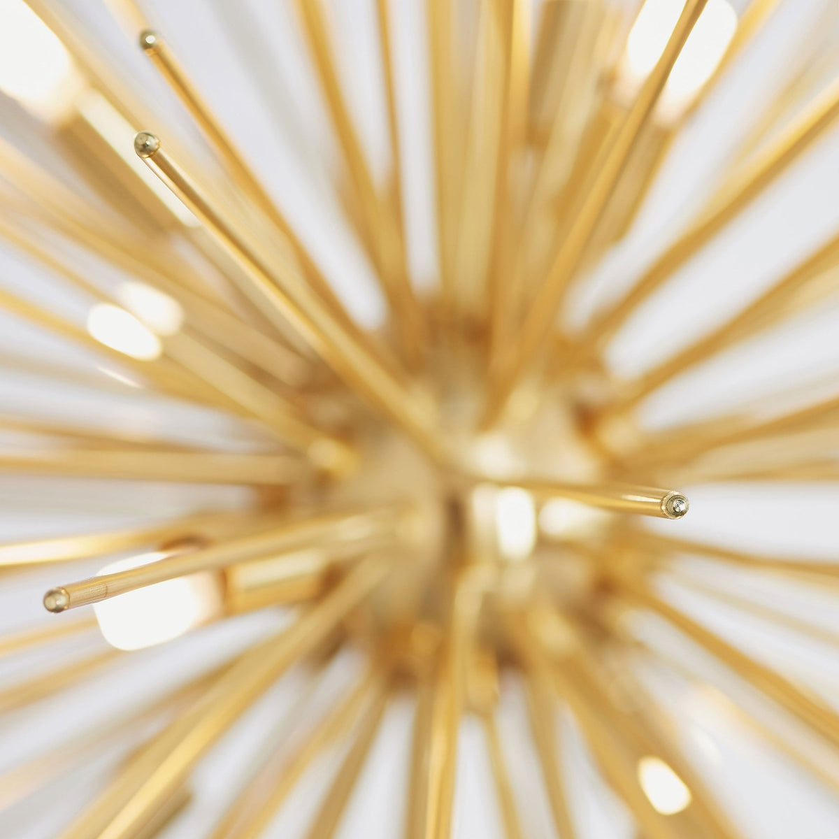 Top-down, blurred view of the gold sputnik chandelier, emphasizing its radial design and glowing bulbs.