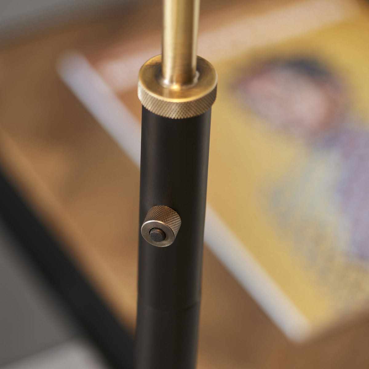 Detail of the lamp's black metal pole with a brass accent and a subtle integrated switch.