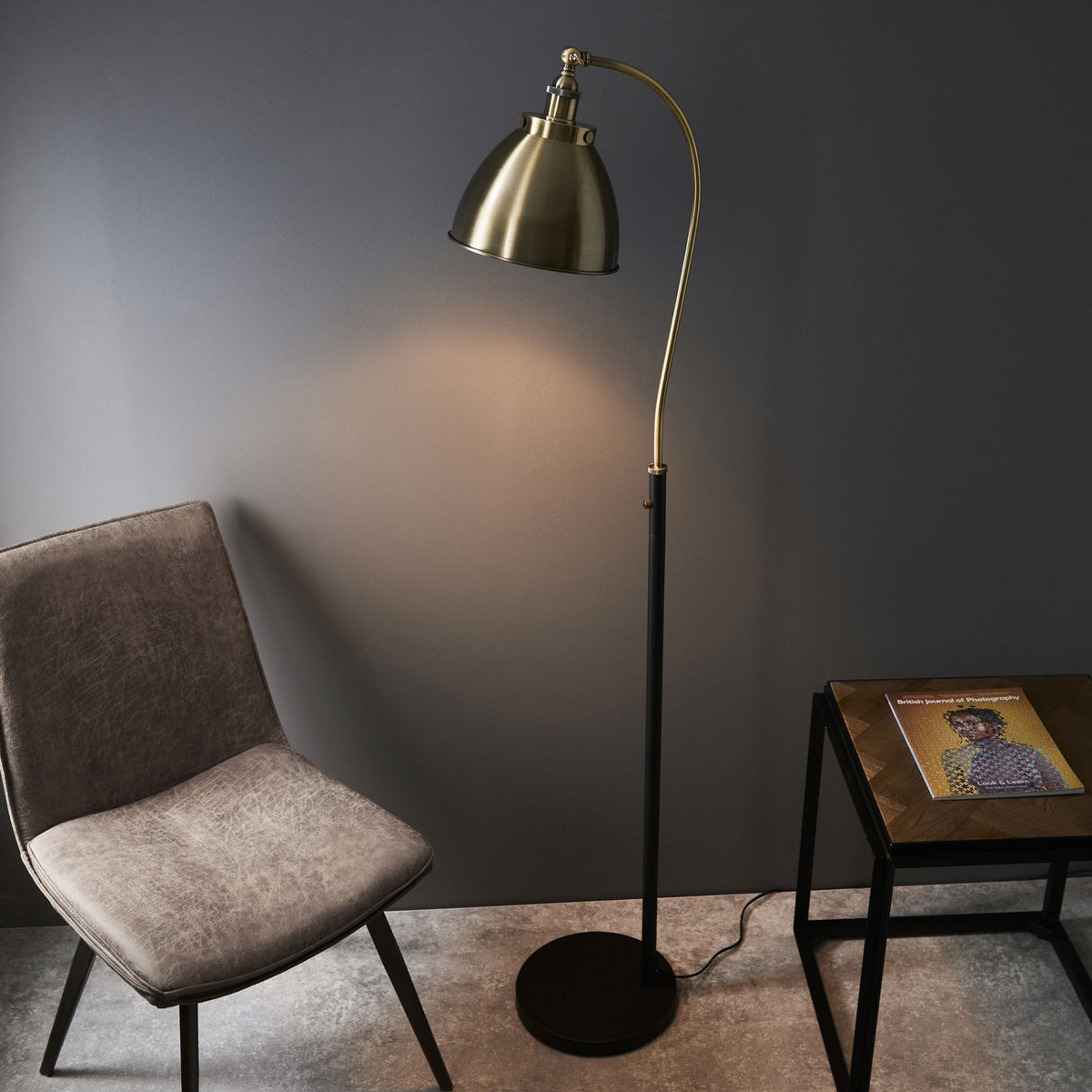 A bronze floor lamp illuminating a cozy corner with a beige chair and side table.
