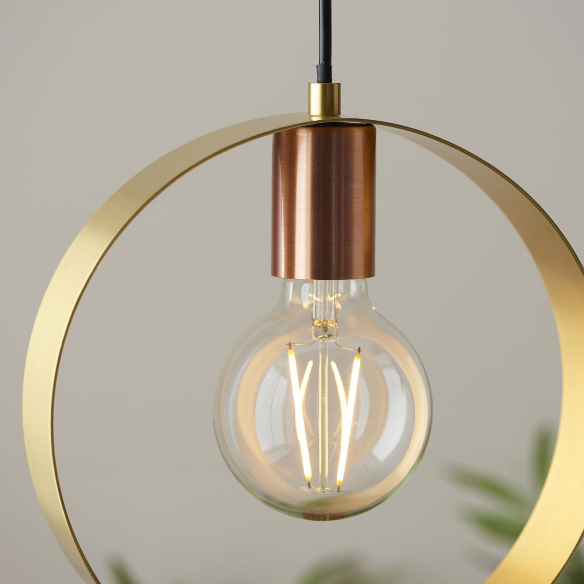 A close-up of the pendant light, highlighting the LED filament bulb, brass ring, and copper accent.
