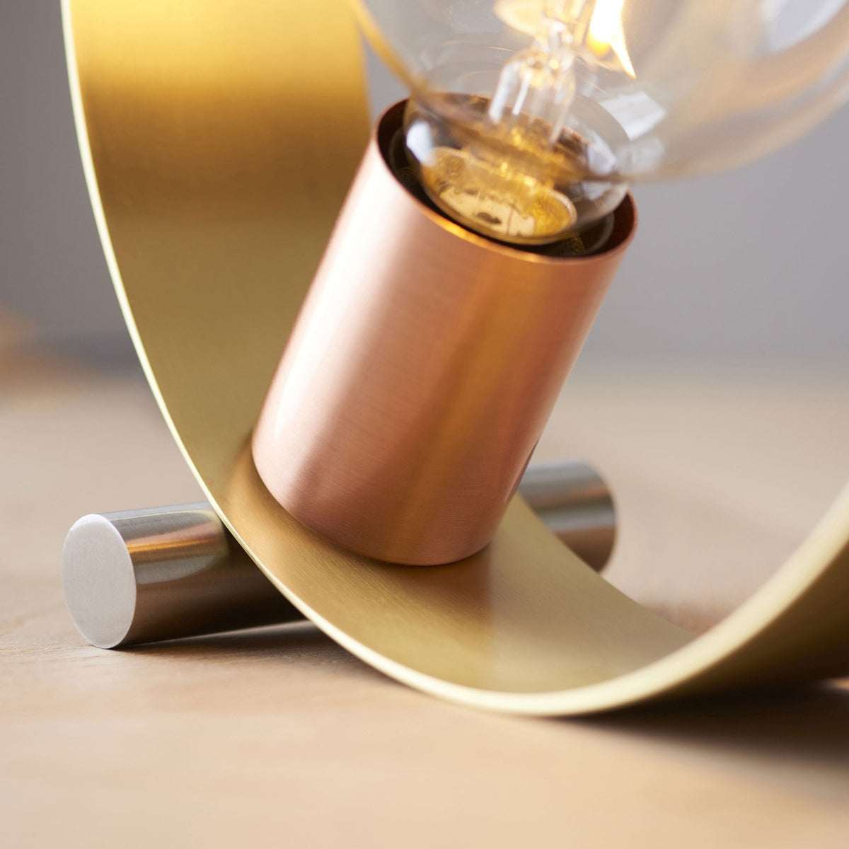 A close-up view of the copper bulb holder and brass ring of the table lamp, showing its base.