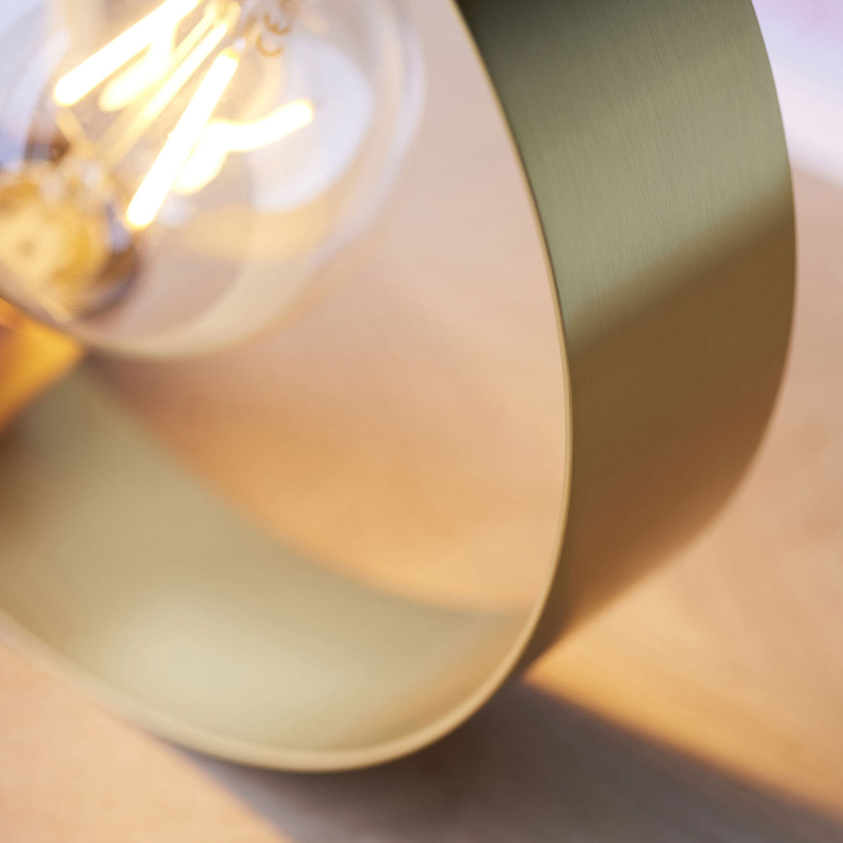 A close-up of the brass ring and an exposed bulb, highlighting the warm glow and metallic texture.