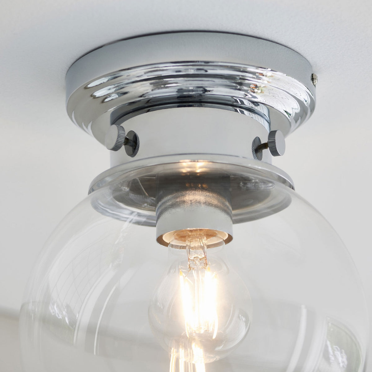 Detail of a flush mount ceiling light, showing the chrome fitting and exposed bulb.