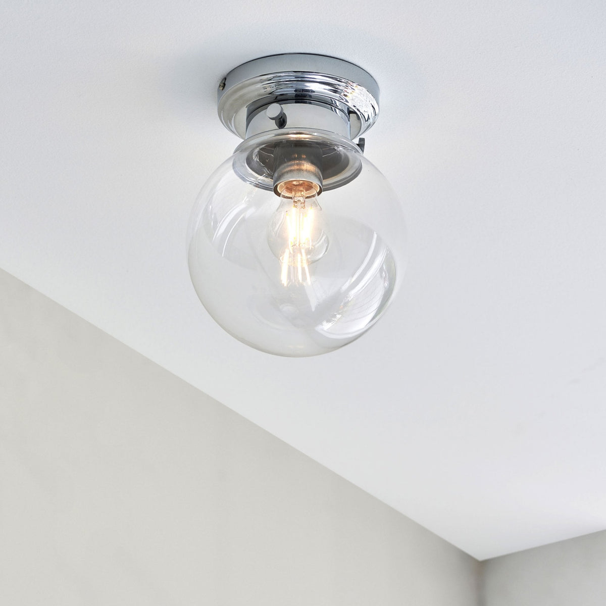 A stylish flush mount ceiling light with a clear glass globe on a white ceiling.