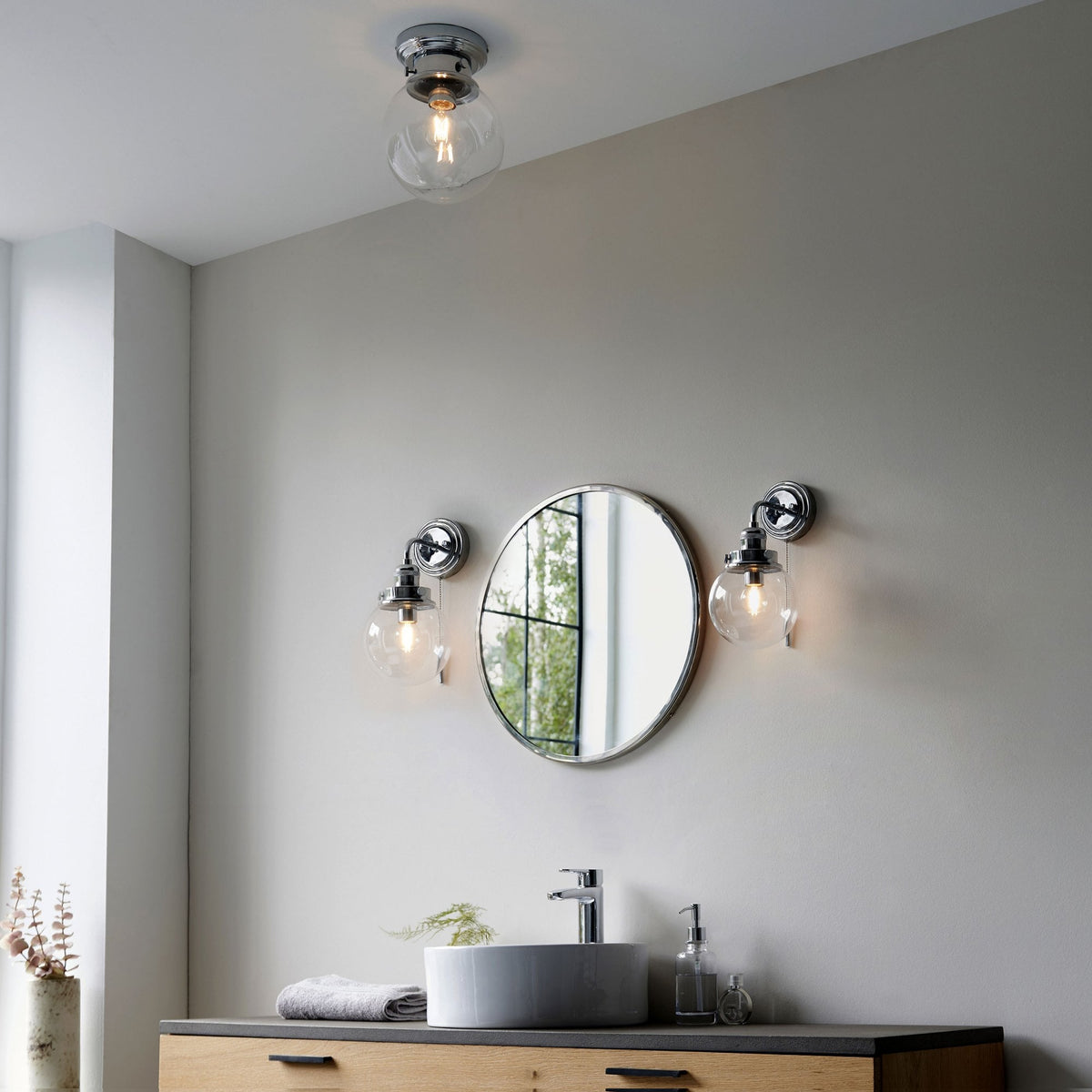 Bathroom interior with a flush mount ceiling light and two matching wall sconces.