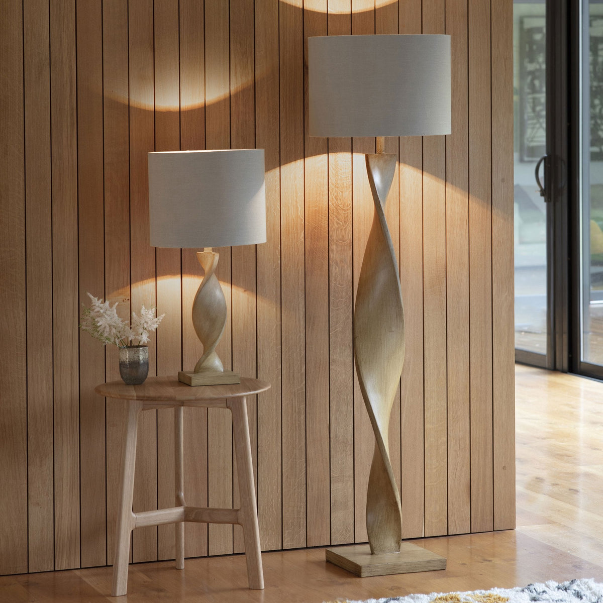 A set of matching lamps, a table lamp and a floor lamp, with twisted wooden bases and neutral shades.