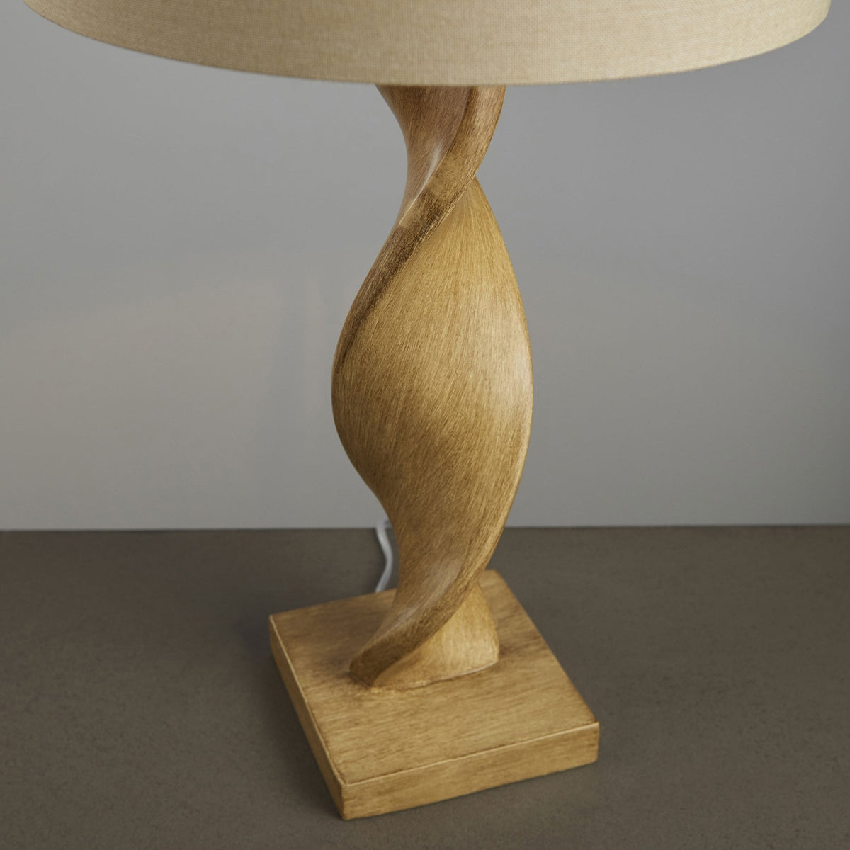 A close-up of the lamp's base and lower twisted stem, highlighting its natural wood grain and texture.