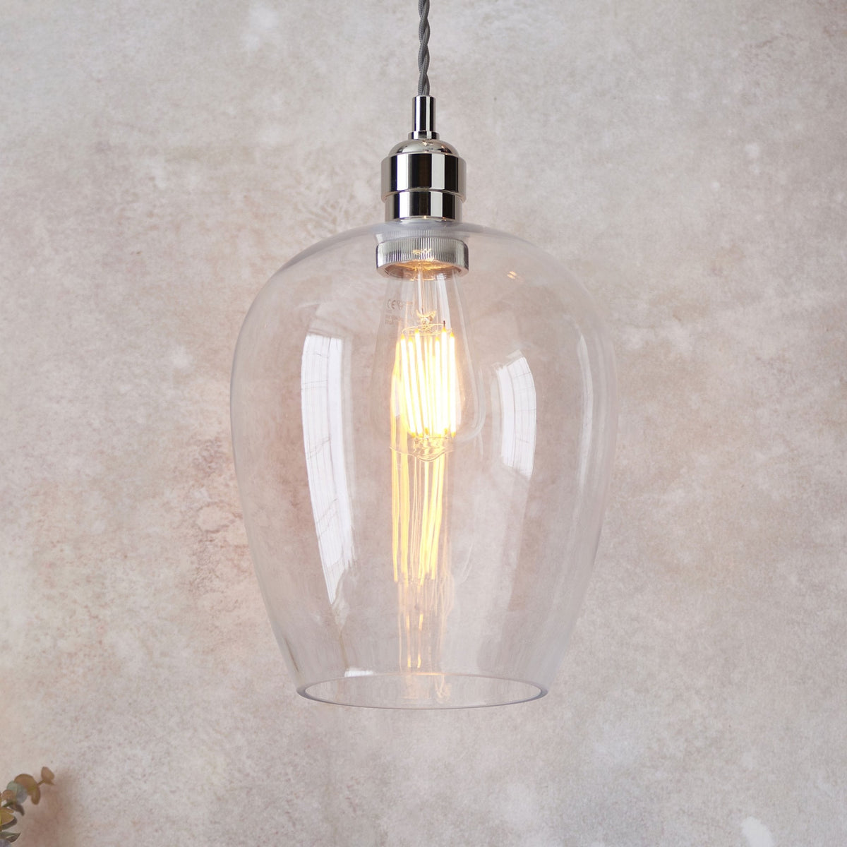 Une ampoule Edison brillante illumine un abat-jour en verre transparent.