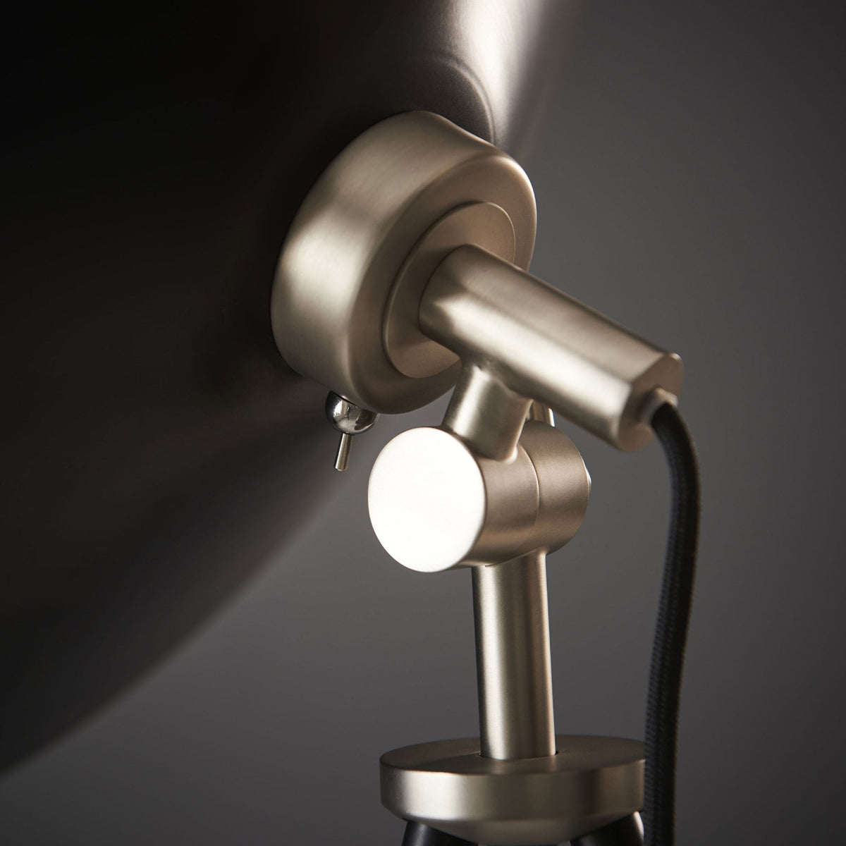 A close-up of the adjustable brushed brass joint on the tripod floor lamp.