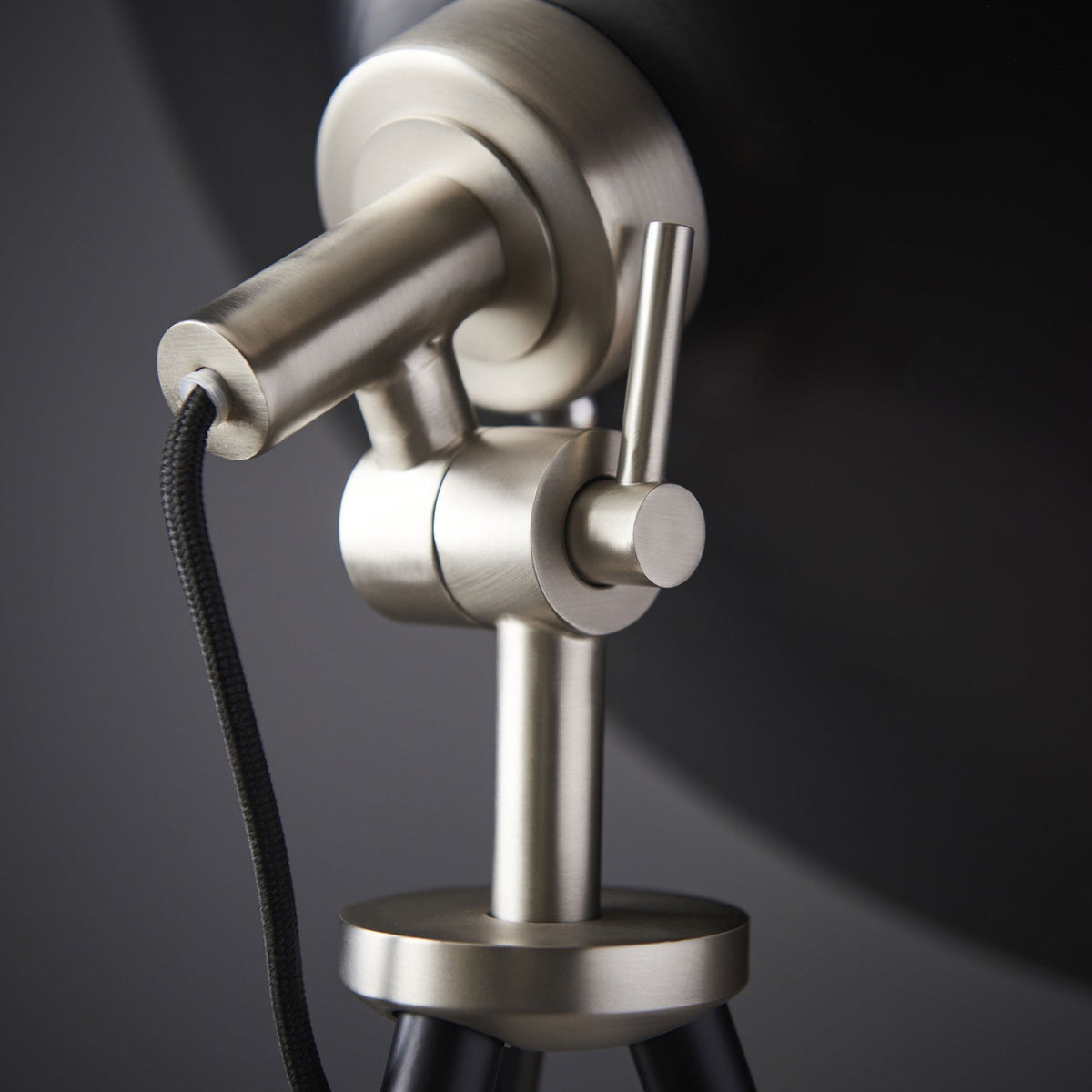 A detailed close-up of the adjustable mechanism on the tripod floor lamp.