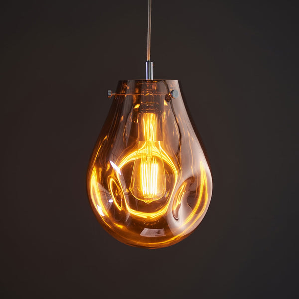 A close-up of a single amber-tinted glass pendant light with a vintage bulb.
