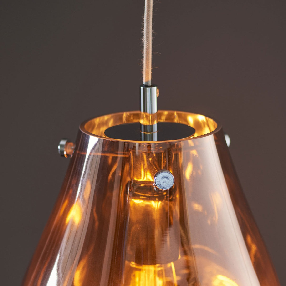 A detailed view of the top of the amber glass pendant light, showing its fitting.