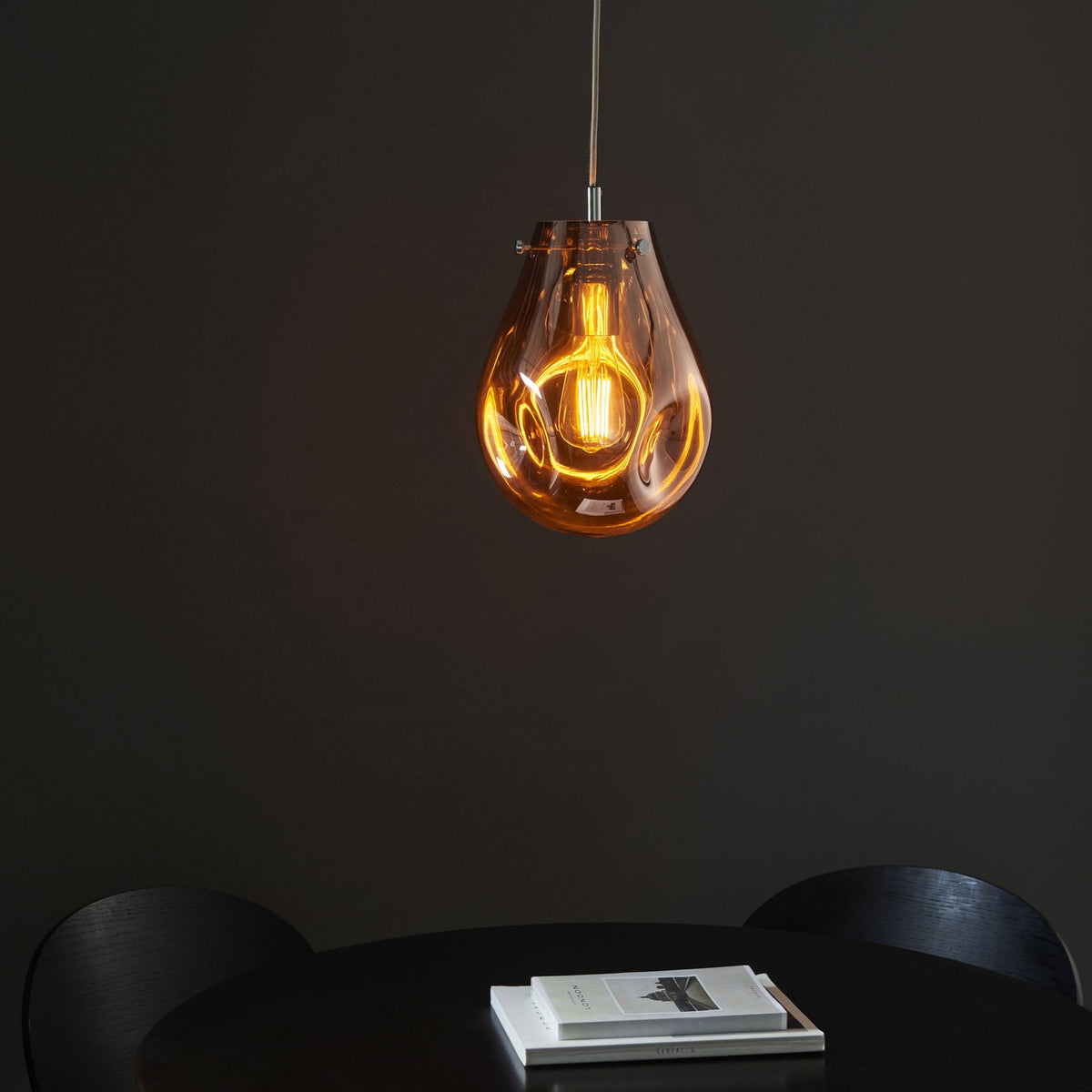 An amber-tinted glass pendant light illuminating a dark dining area.