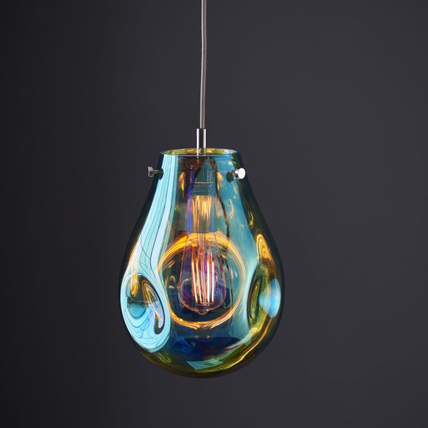 Teardrop pendant light in iridescent blue and amber with a lit filament bulb.