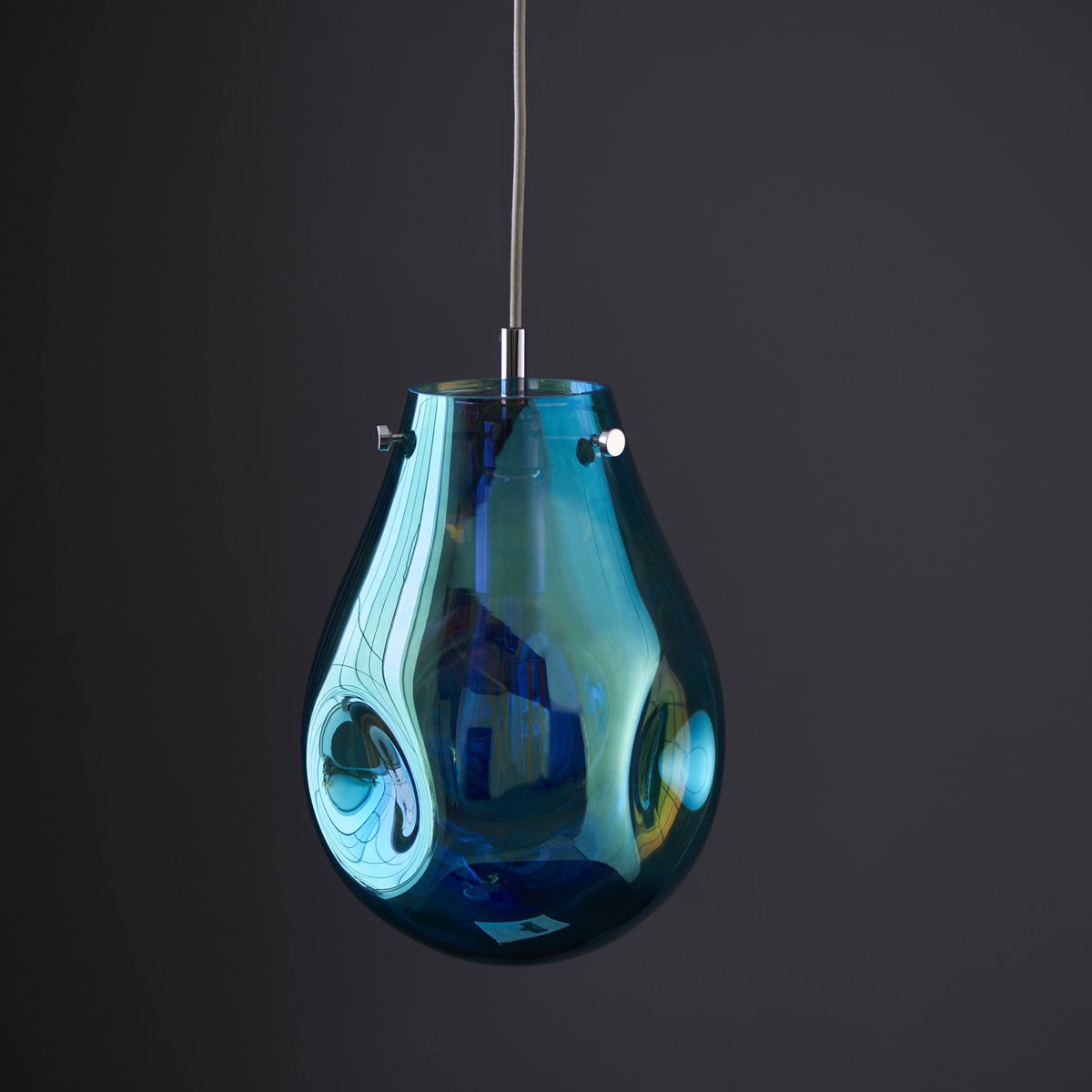 Teardrop pendant light in iridescent blue and amber with an unlit bulb.