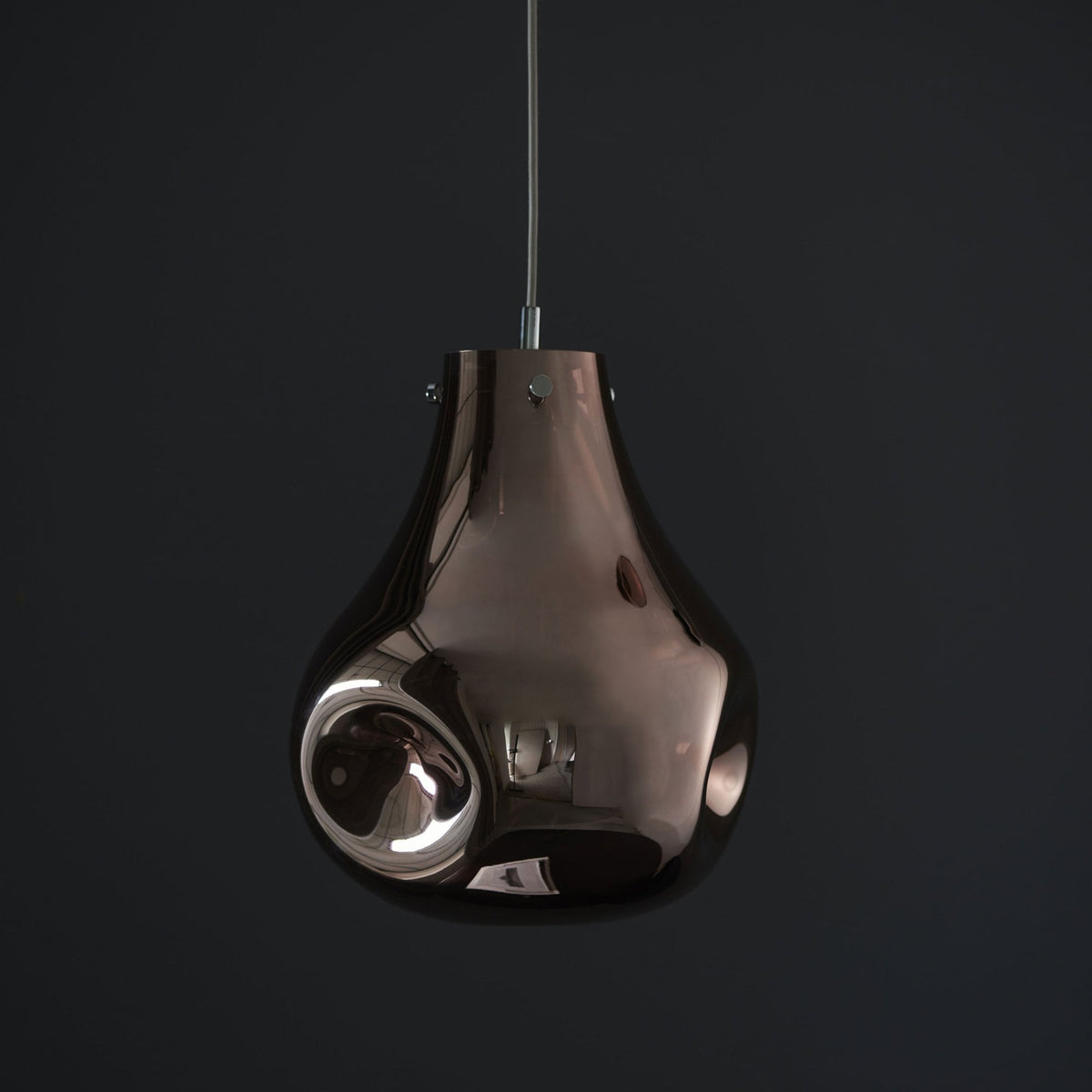A bronze-colored glass pendant light with a distinct, organic, melting shape against a dark background, unlit.