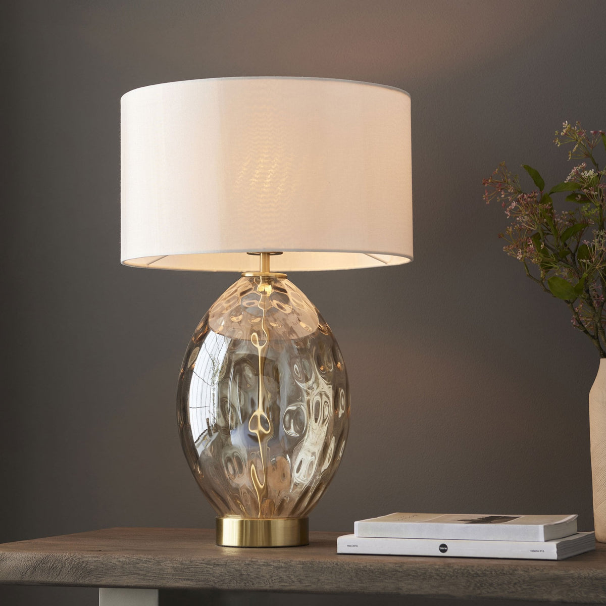 A close up view of the Dimpled Glass Table Lamp with a white shade, and a shiny gold base.