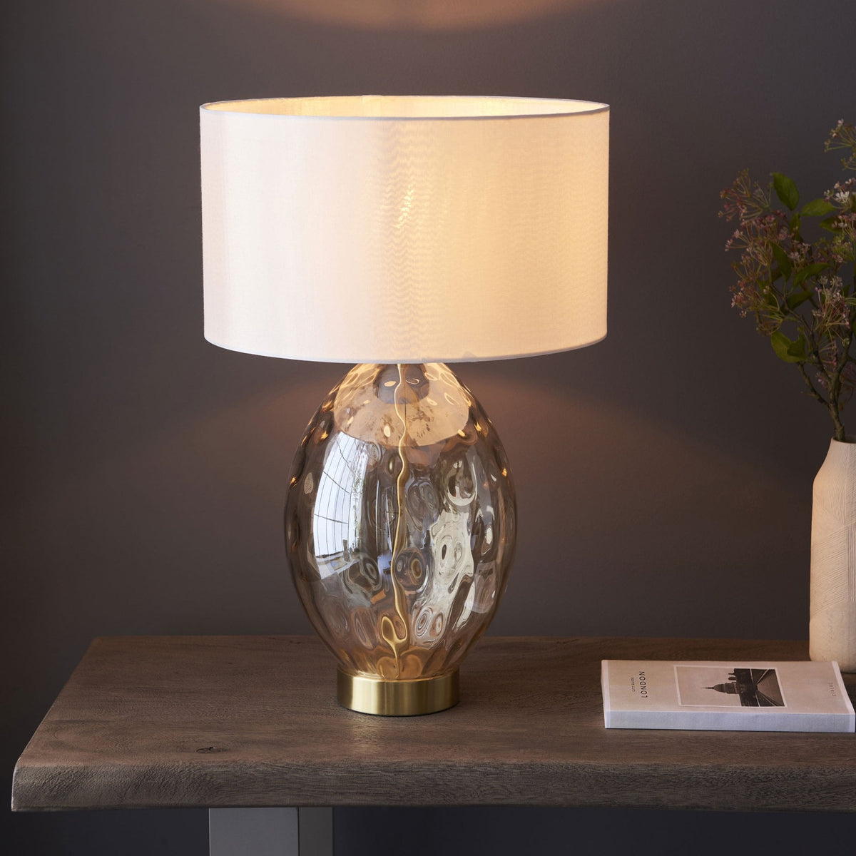 A close up view of the Dimpled Glass Table Lamp with a white shade, and a shiny gold base.